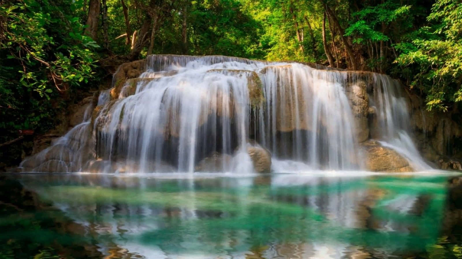 3d Waterfall 桌布 壁紙 — 一個寧靜的多層瀑布傾瀉而下，流入一個被茂密綠色叢林環繞的清澈碧綠水池。