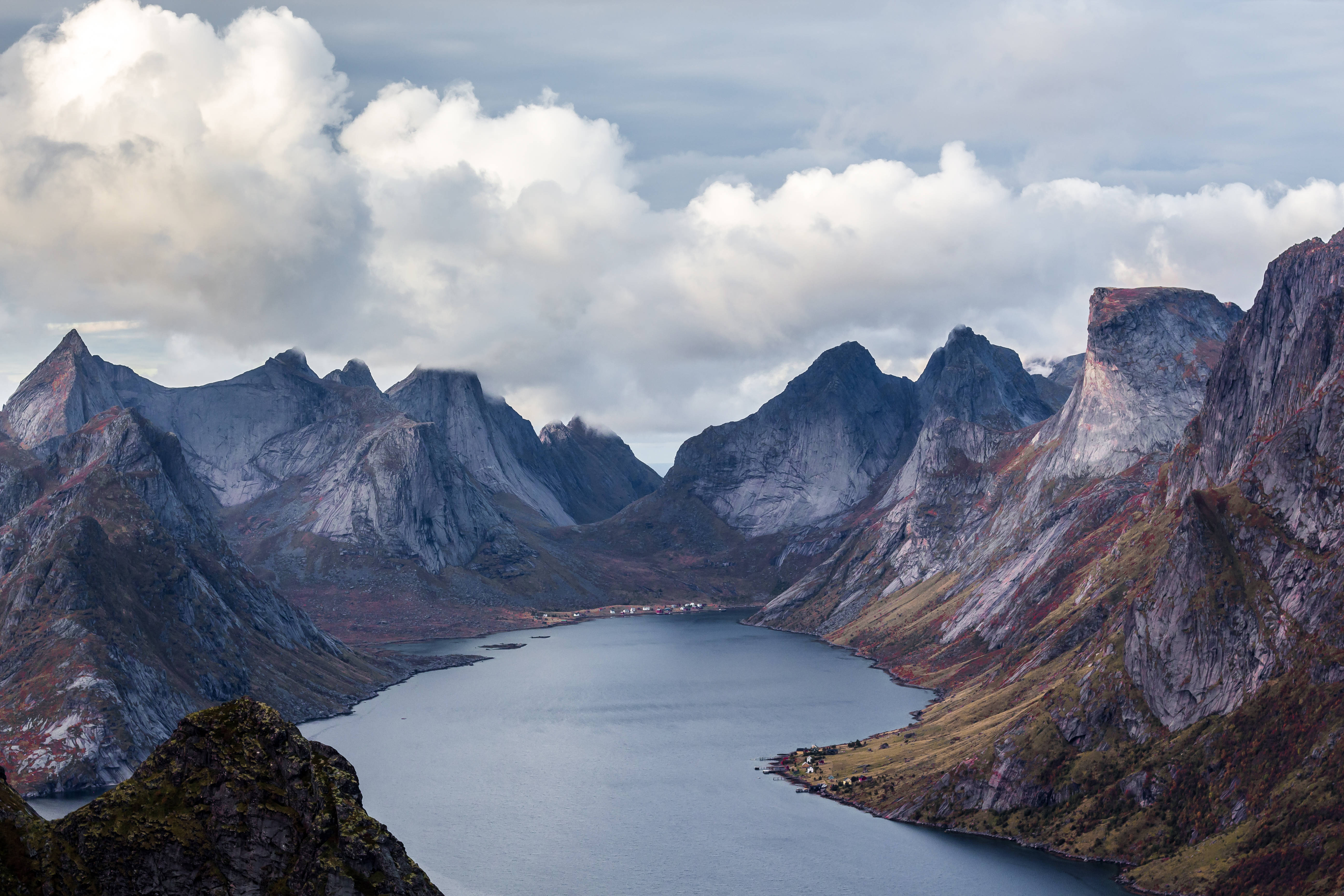 Norway 桌布 壁紙 — 一個寧靜的峽灣，坐落於高聳崎嶇的山脈之間，天空多雲。
