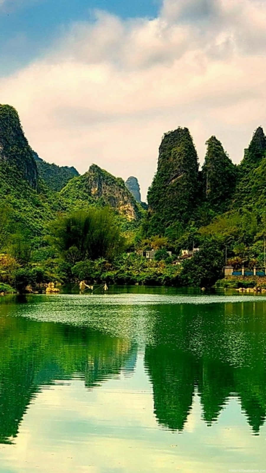 美景 桌布 壁紙 — 一個寧靜的湖泊在部分多雲的天空下，映照出鬱鬱蔥蔥的綠色喀斯特山脈，帶有鮮豔的倒影。