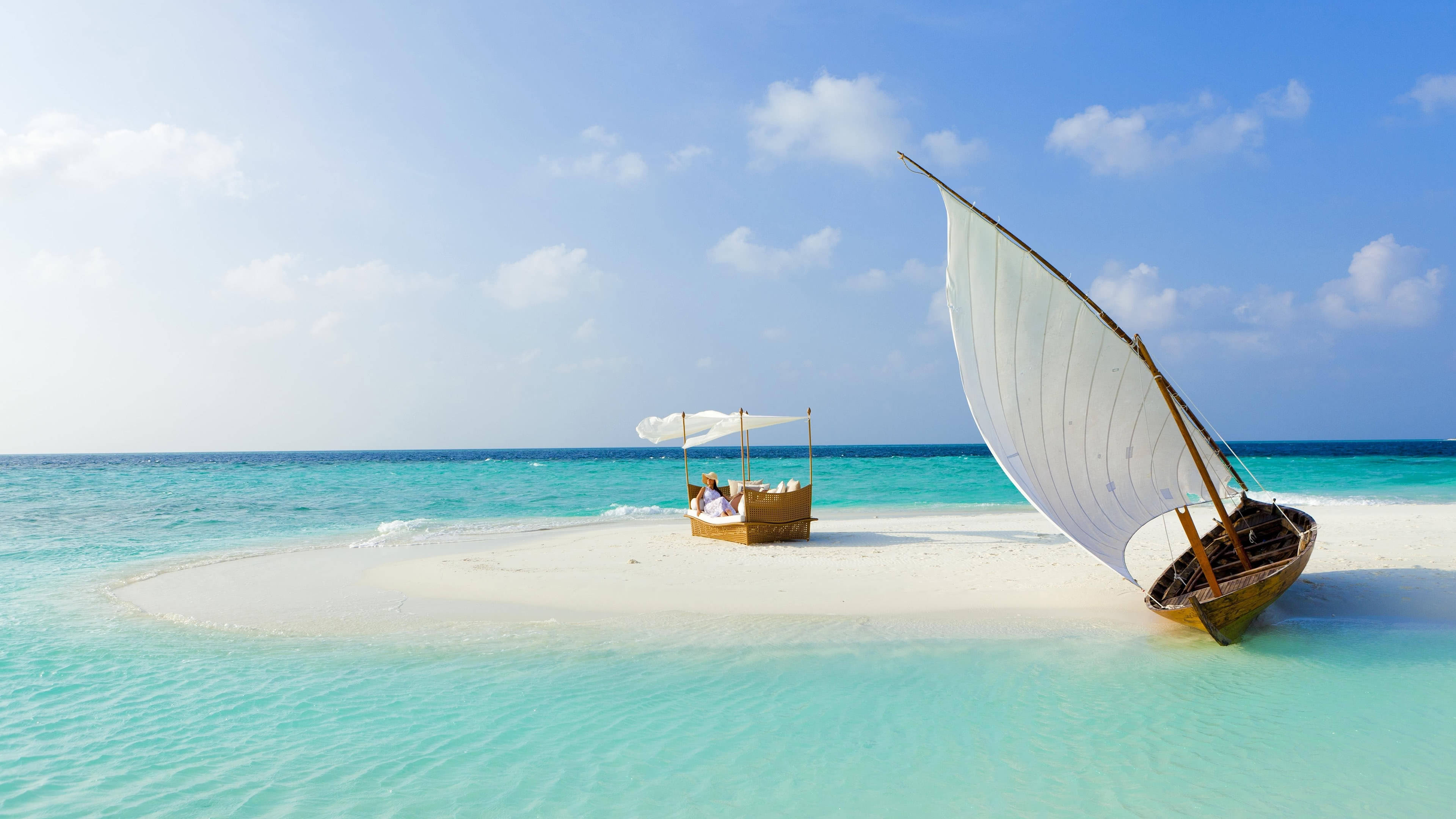 Sail Boat White Beach 壁紙 — 一個寧靜的熱帶島嶼，擁有碧綠的海水和一艘傳統帆船停泊在沙灘附近。
