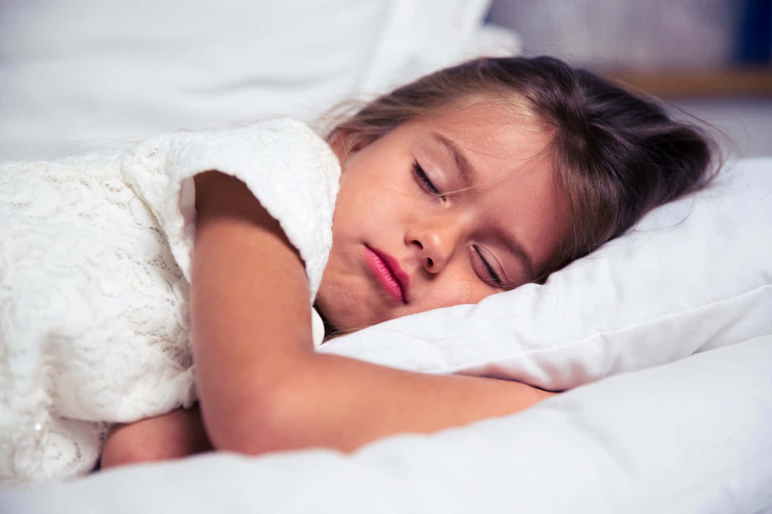 Sleep 桌布 壁紙 — 一個小女孩在柔和的燈光下，包裹著帶蕾絲邊的白色毯子，安詳地睡在白色枕頭上。