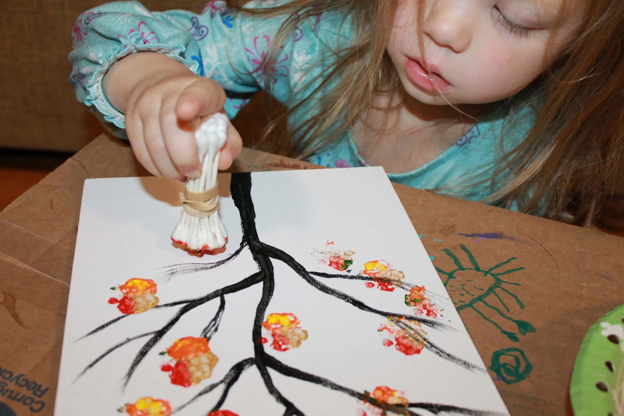 Fall Crafts 桌布 壁紙 — 一個小孩用自製畫筆在白色紙上的黑色樹木畫中添加彩色樹葉印記。