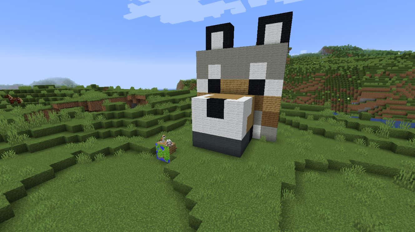 Minecraft Pixel Art 桌布 壁紙 — 一個巨大的像素化狐狸頭雕塑矗立在晴朗藍天下、長滿草的Minecraft景觀中。