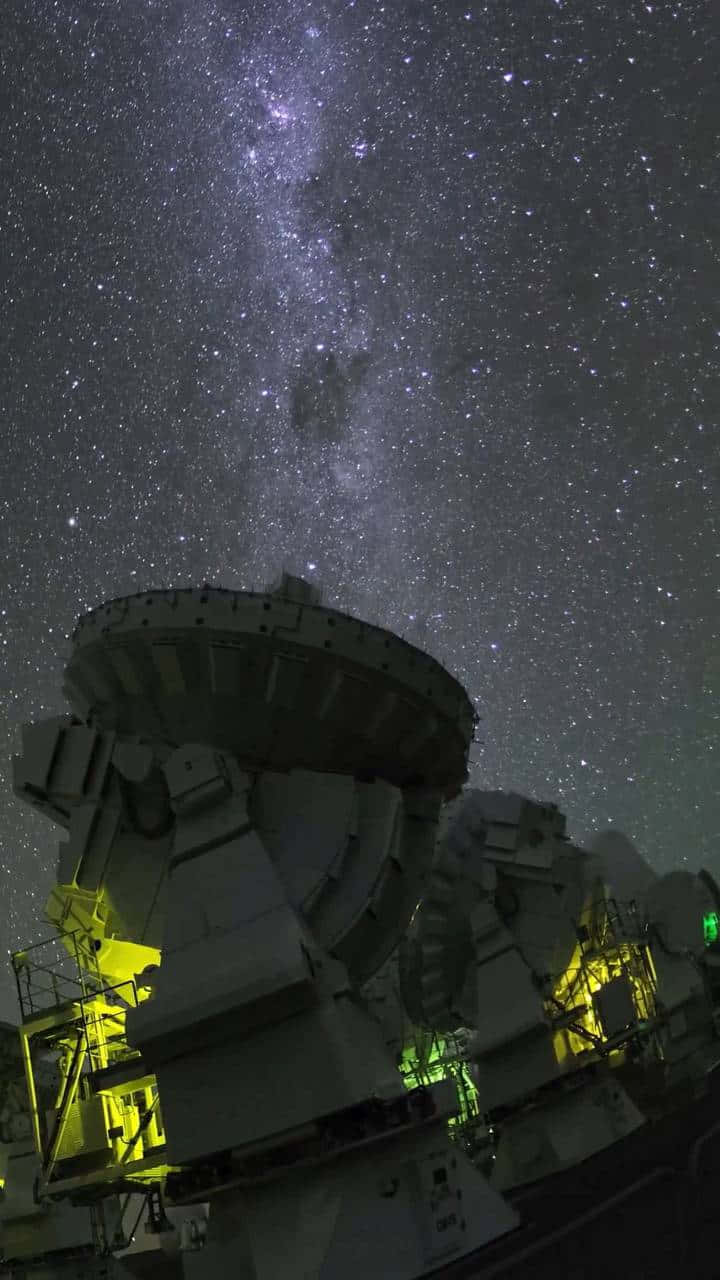 Space Observation 桌布 壁紙 — 一個巨大的無線電望遠鏡矗立在繁星點點的夜空下，銀河在上方閃耀。