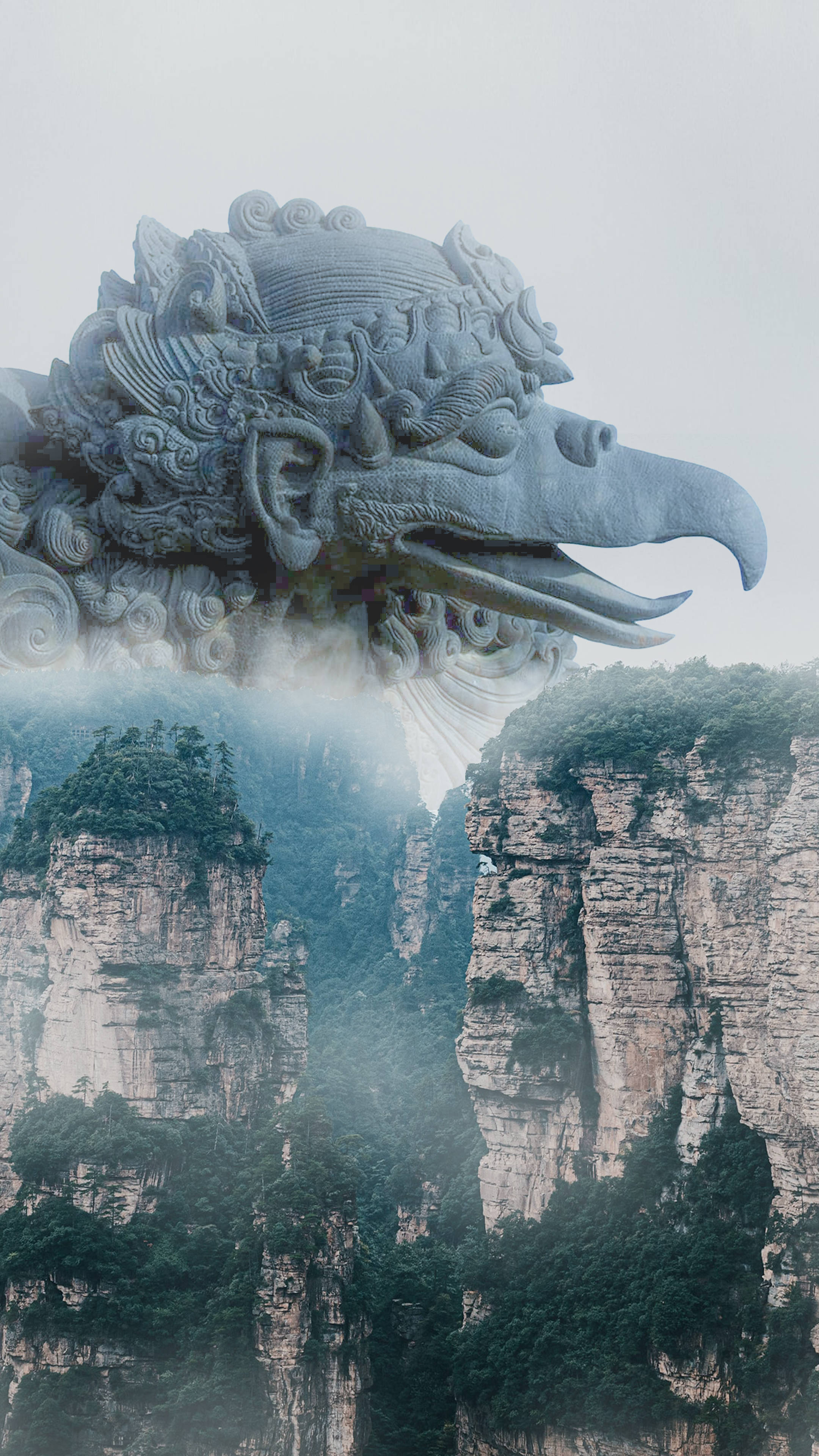Statue Aesthetic 桌布 壁紙 — 一個巨大的石龍頭從煙霧繚繞的山峰中浮現，茂密的綠色森林緊貼在陡峭的懸崖上。