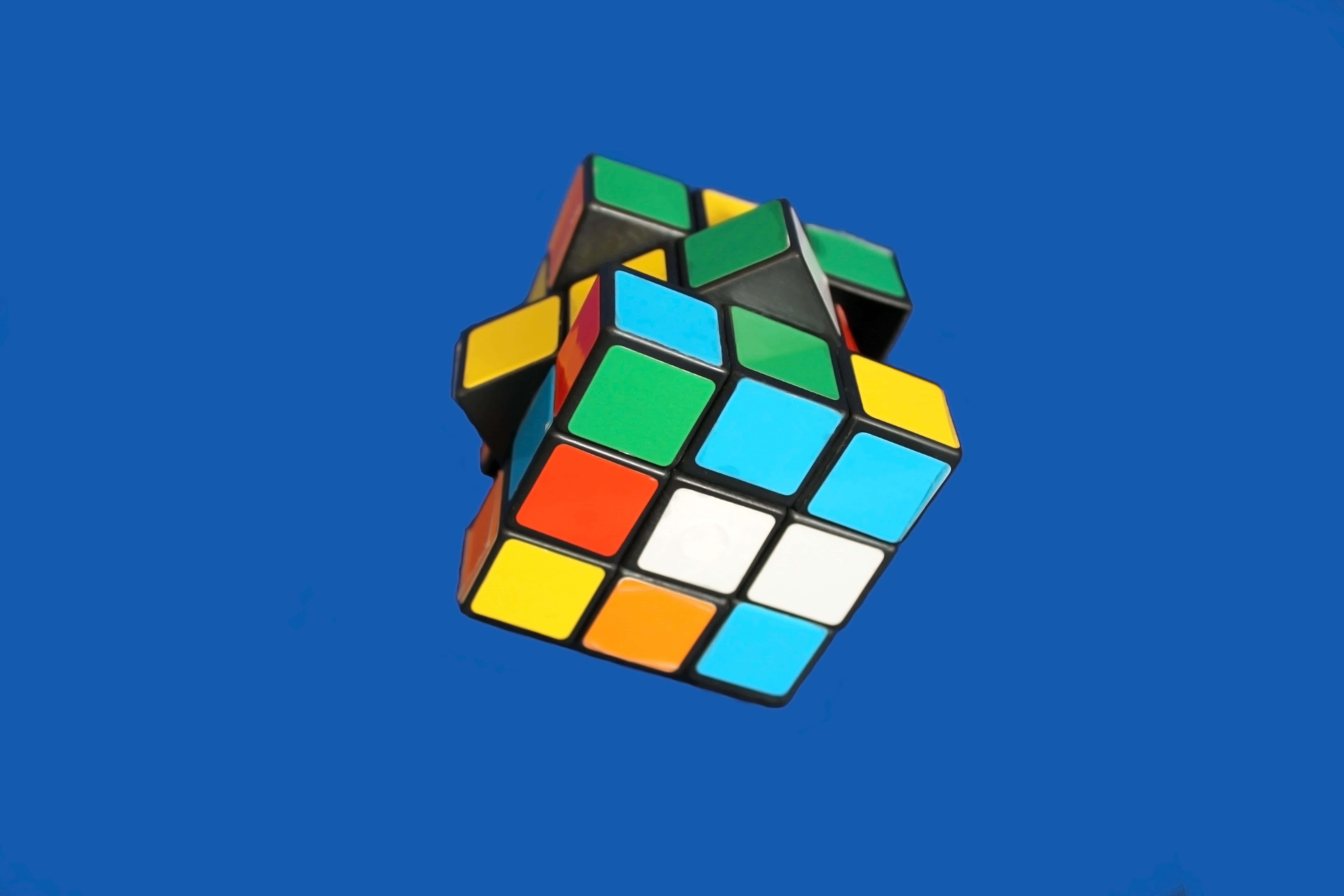 Educational Games 桌布 壁紙 — 一個已解開的扭計骰漂浮在純藍色背景上，帶有鮮豔的彩色方格。