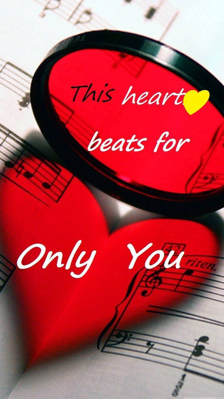 Love Quotes 桌布 壁紙 — 一個帶有文字的光澤紅色心形物體放在樂譜上，傳達浪漫的音樂奉獻。