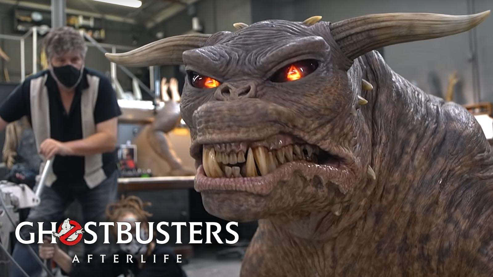Ghostbusters 桌布 壁紙 — 一個帶有發光紅眼和尖銳牙齒的威脅性有角怪物在電影製片廠場景中若隱若現。