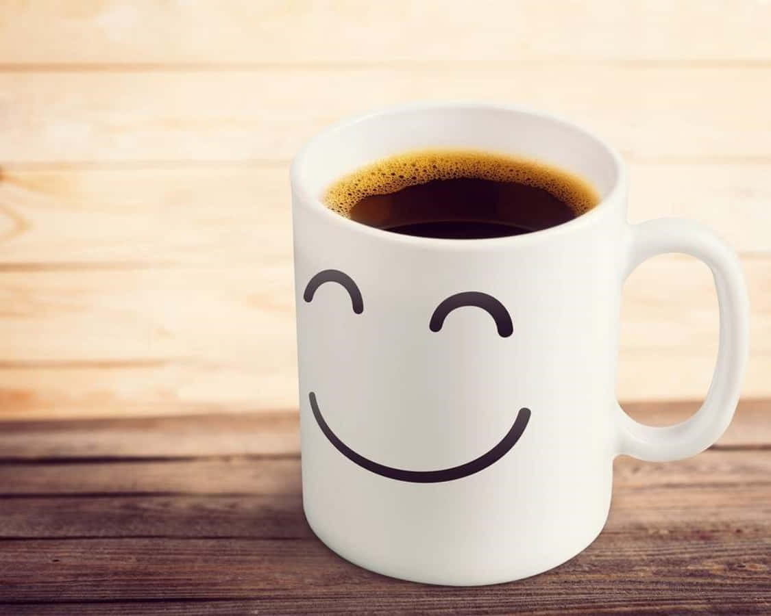 Coffee Cup 桌布 壁紙 — 一個帶有簡單笑臉設計的白色馬克杯，在溫暖的木質表面上盛著黑咖啡。