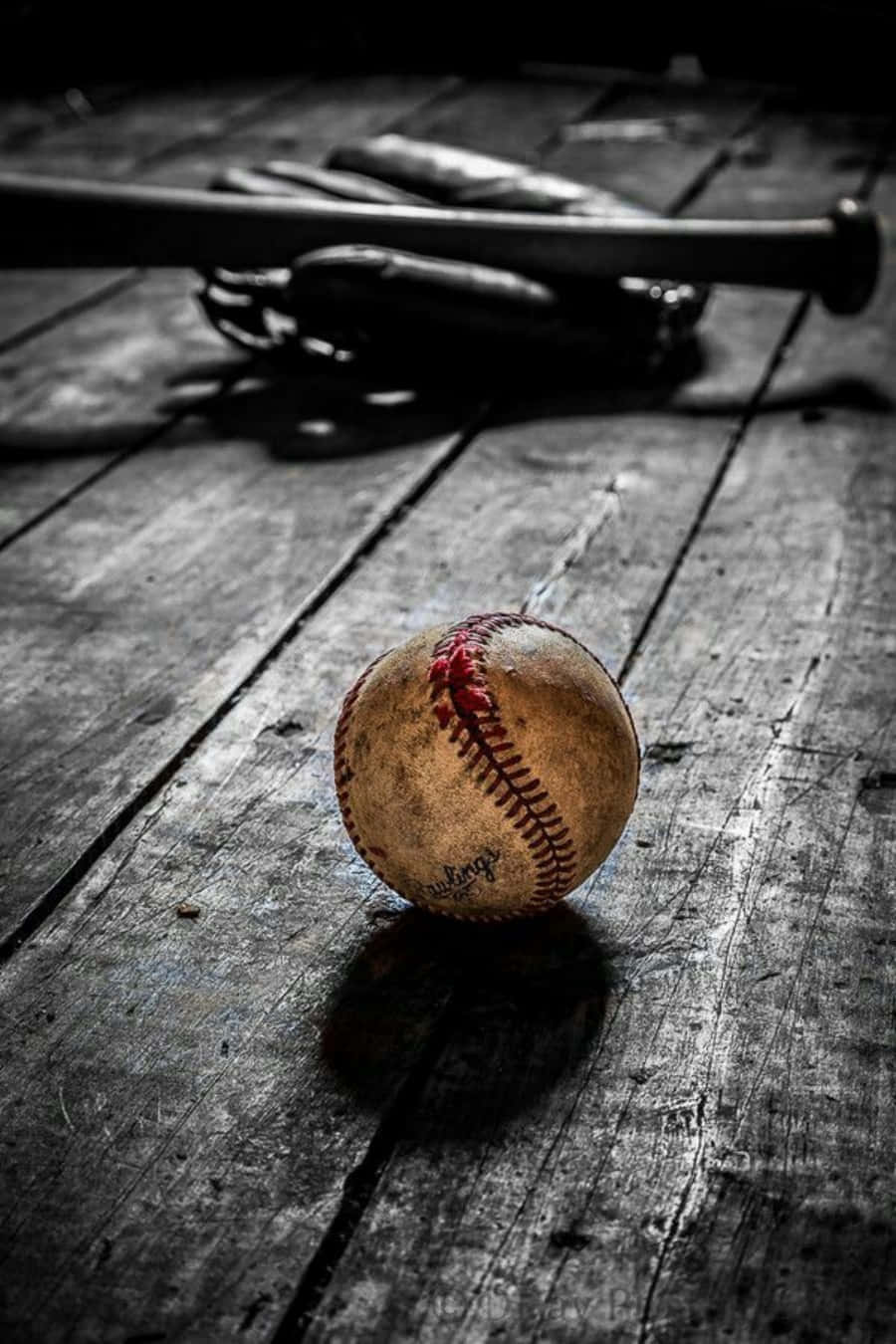 Cool Baseball 桌布 壁紙 — 一個帶有紅色縫線的風化棒球放在深色木地板上，旁邊有交叉的球棒和手套。