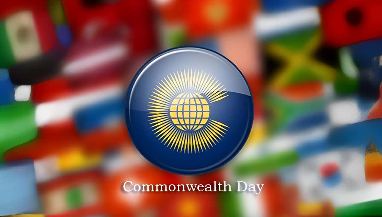 Commonwealth Day 桌布 壁紙 — 一個帶有金色地球和太陽爆發的亮藍色圓形英聯邦日標誌，背景是模糊的國際旗幟馬賽克。