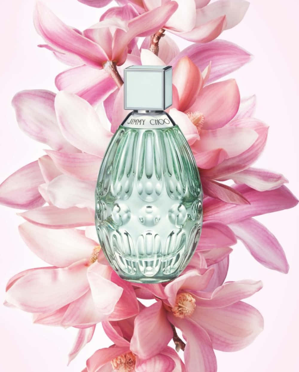 Floral Fragrance 桌布 壁紙 — 一個帶有銀色蓋子的紋理綠色香水瓶，依偎在柔和的粉紅色木蘭花中，背景是淡粉色。
