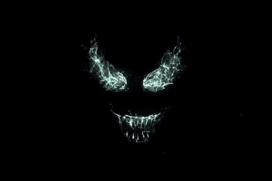 Venom Logo 桌布 壁紙 — 一個帶有鋸齒狀牙齒和火紅眼睛的威脅性發光白色骷髏從純黑色黑暗中浮現。