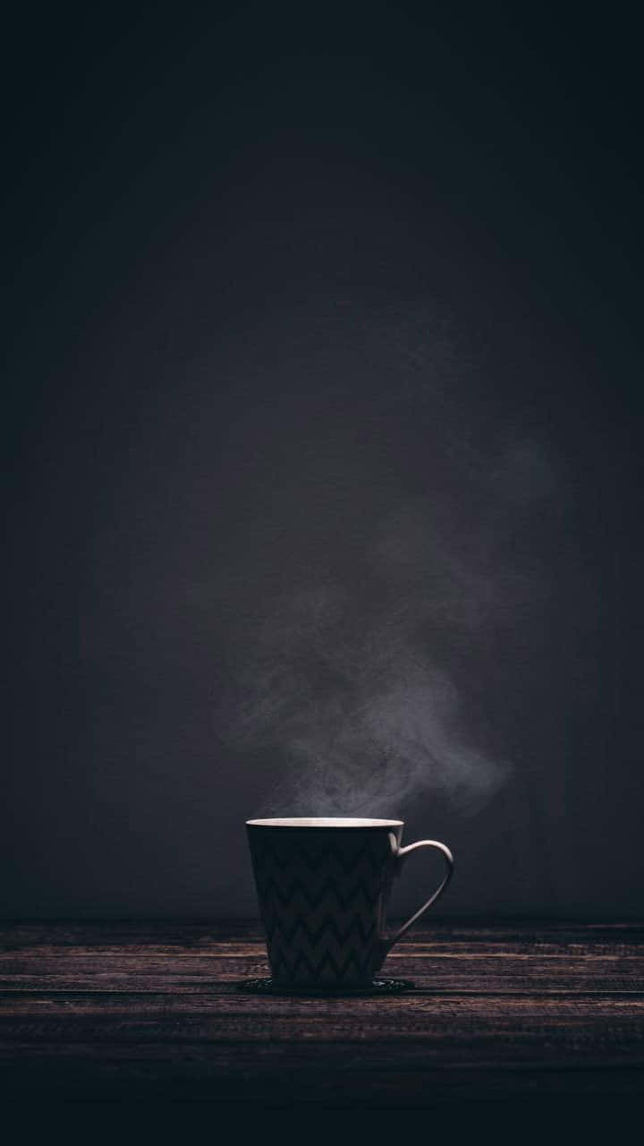 Minimalist Coffee 桌布 壁紙 — 一個帶有鋸齒紋的冒煙馬克杯獨自放在深色木桌上，背景是煙灰色。