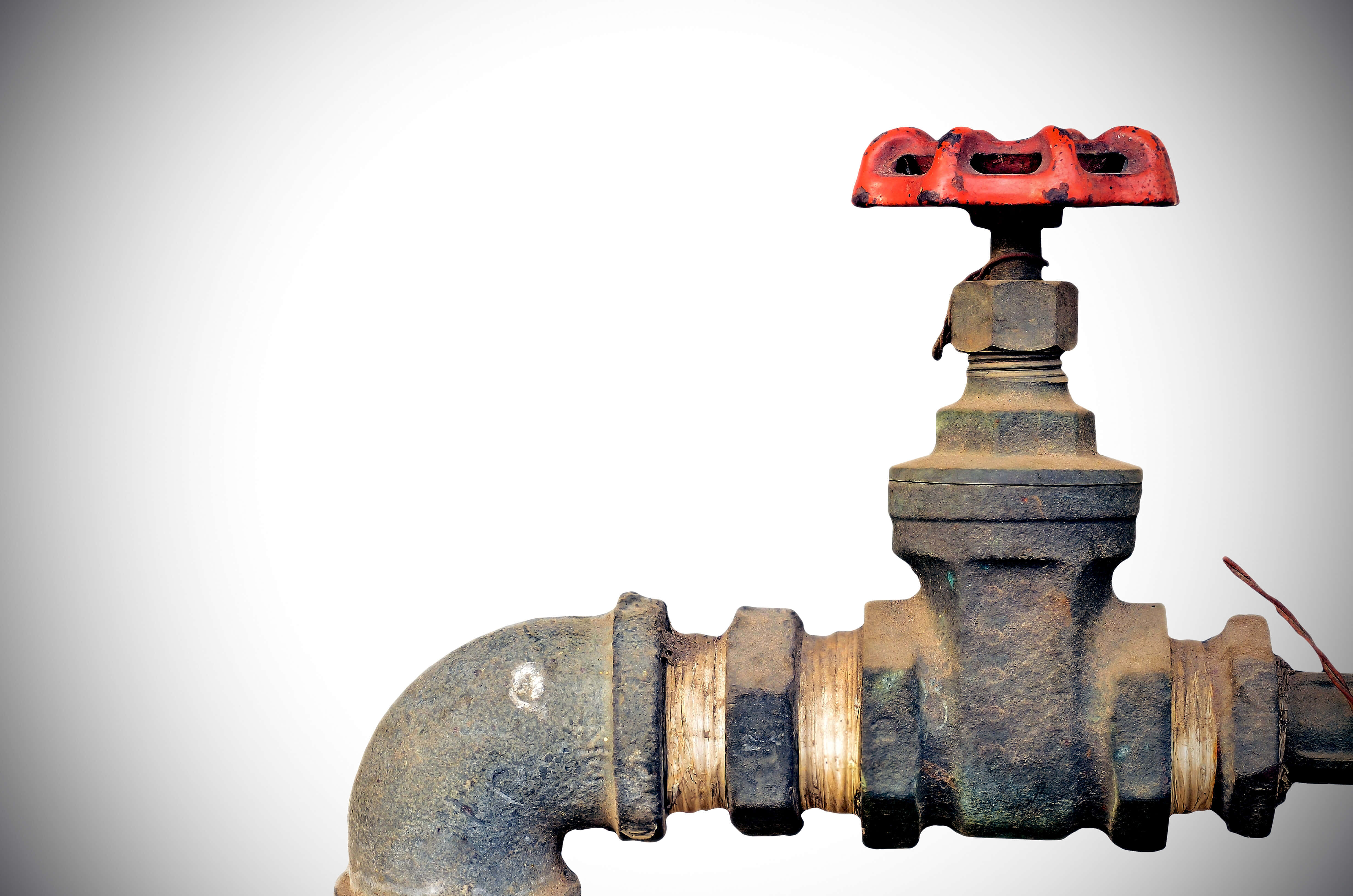Plumbing 桌布 壁紙 — 一個帶有鮮紅色手柄的風化工業水閥，在純白色背景上格外突出。