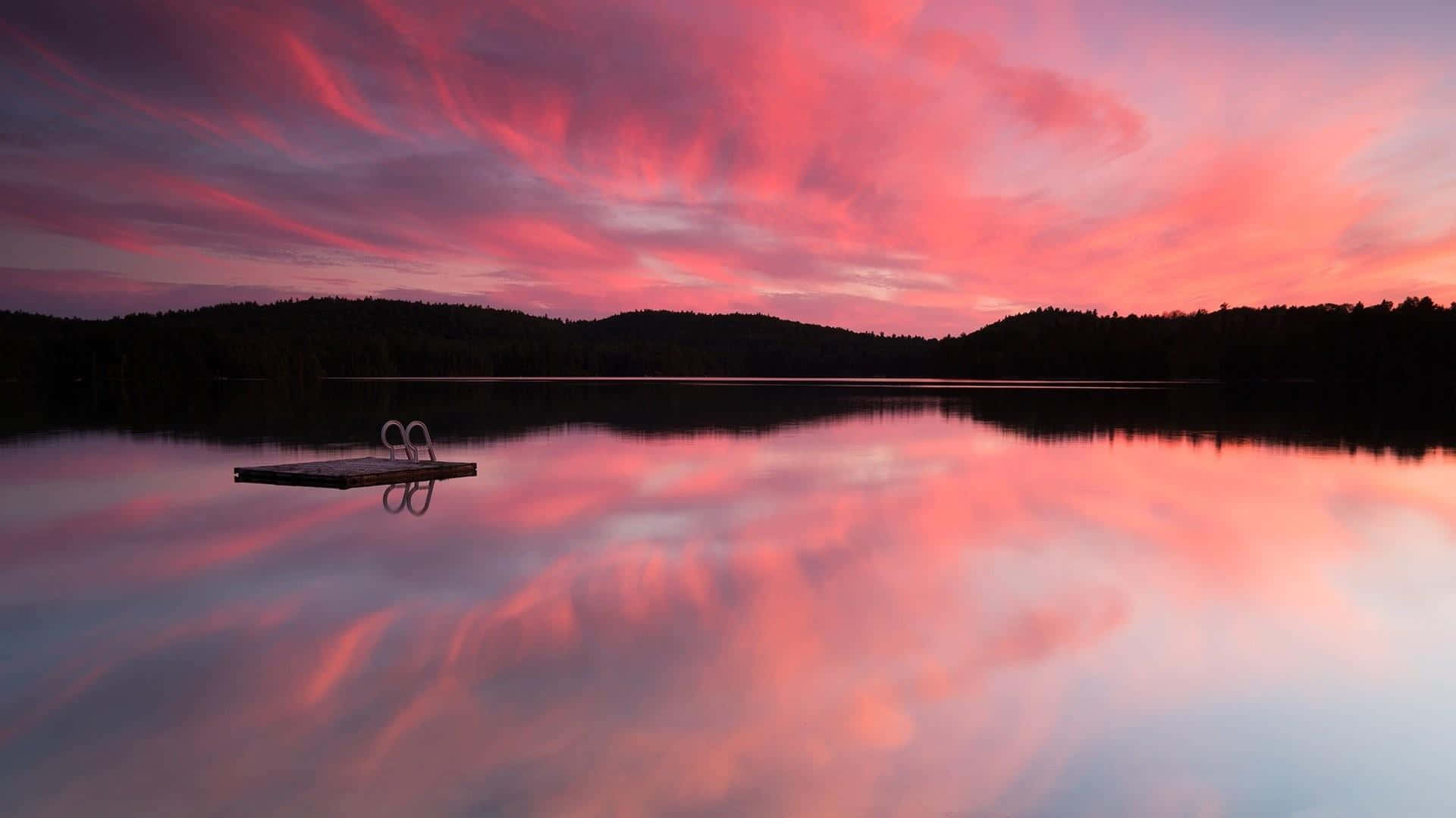Sunset Reflection 桌布 壁紙 — 一個帶梯子的木製碼頭延伸到平靜的湖中，映照出戲劇性的粉紅色和紫色日落天空。
