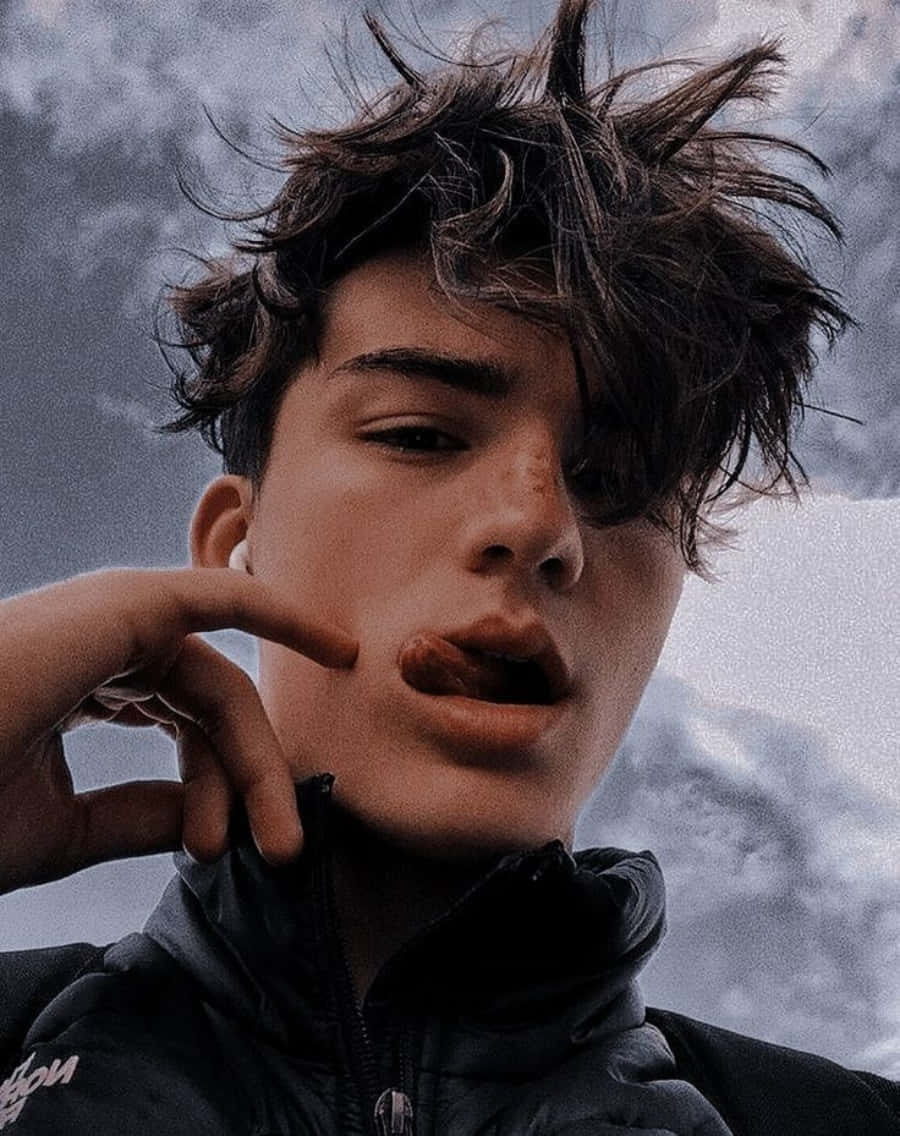 Boy 桌布 壁紙 — 一個年輕男子，凌亂的深色頭髮和雀斑，穿著黑色夾克，在陰天背景下擺姿勢。