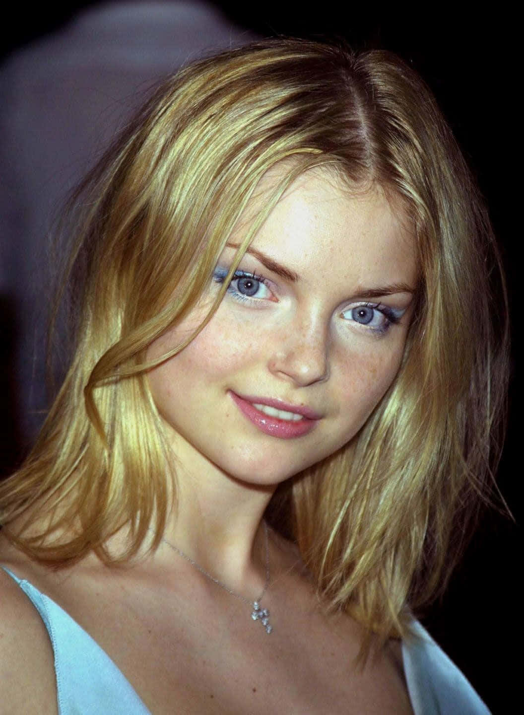 Izabella Miko 桌布 壁紙 — 一個年輕金髮碧眼女子在深色背景前微笑的特寫肖像。