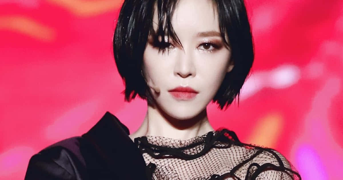 Brown Eyed Girl 桌布 壁紙 — 一個引人注目的肖像，短黑髮和鮮豔妝容的女性，背景是鮮紅色的模糊背景。