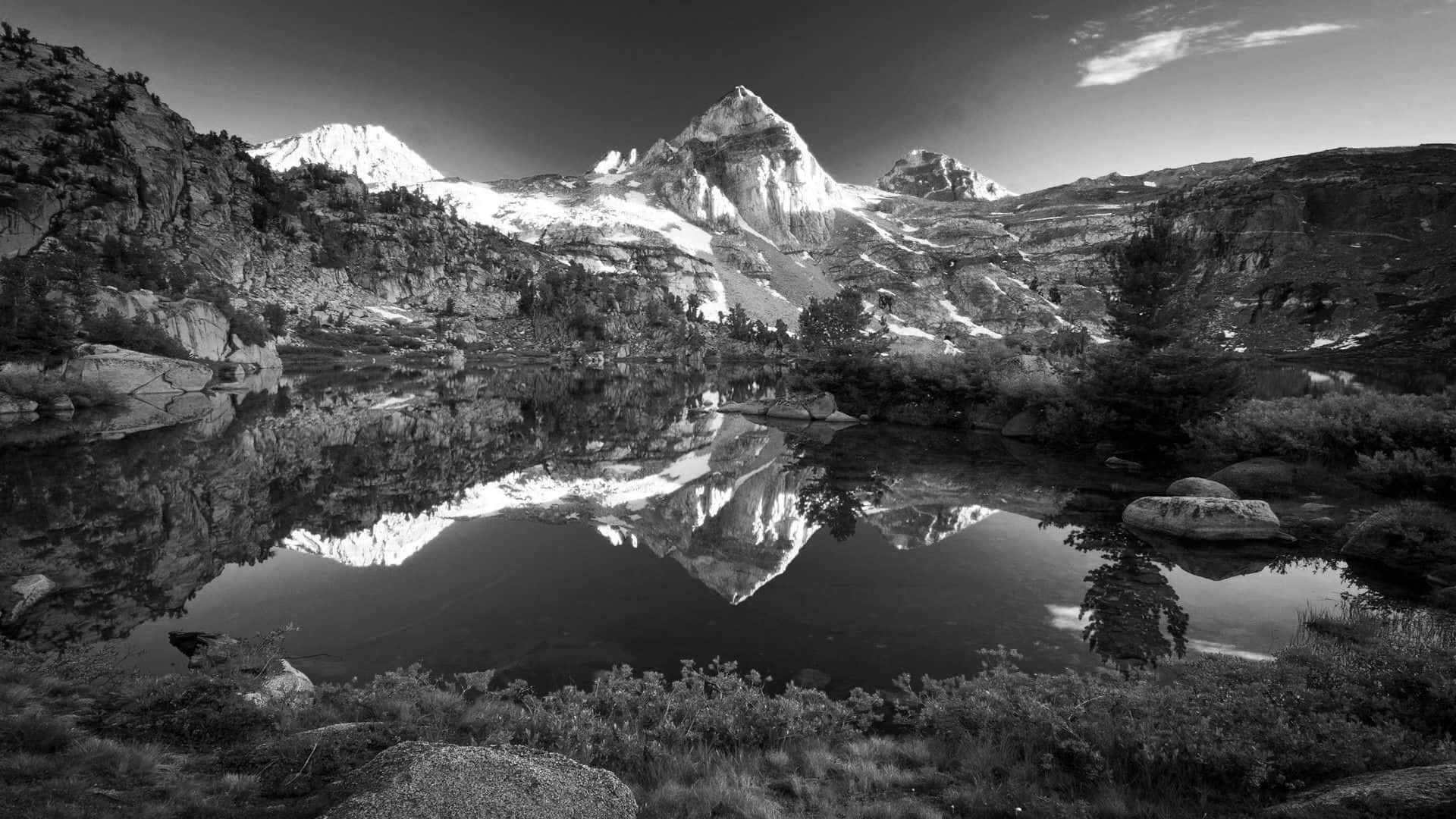 Black And White Landscape 桌布 壁紙 — 一個引人注目的黑白山景，雪覆蓋的山峰完美地倒映在一個被岩石地形包圍的寧靜高山湖泊中。