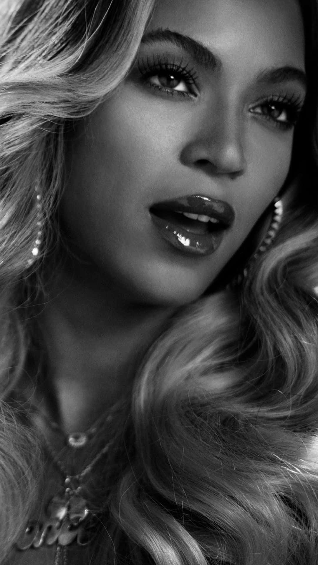 Beyoncé 桌布 壁紙 — 一個引人注目的黑白特寫肖像，描繪一位擁有豐盈捲髮和光澤嘴唇的女性，直視觀眾。