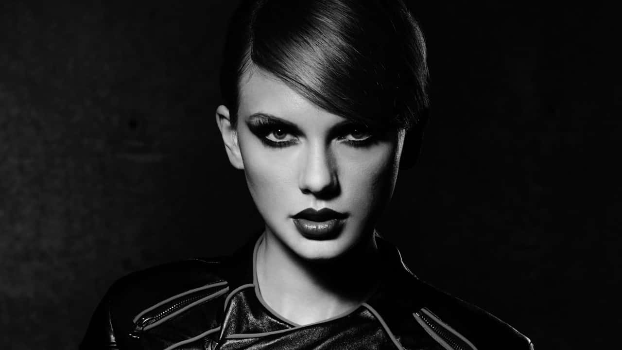 Black And White Celebrity 桌布 壁紙 — 一個引人注目的黑白肖像，一位女性化著大膽妝容、身穿皮夾克，專注地凝視鏡頭。