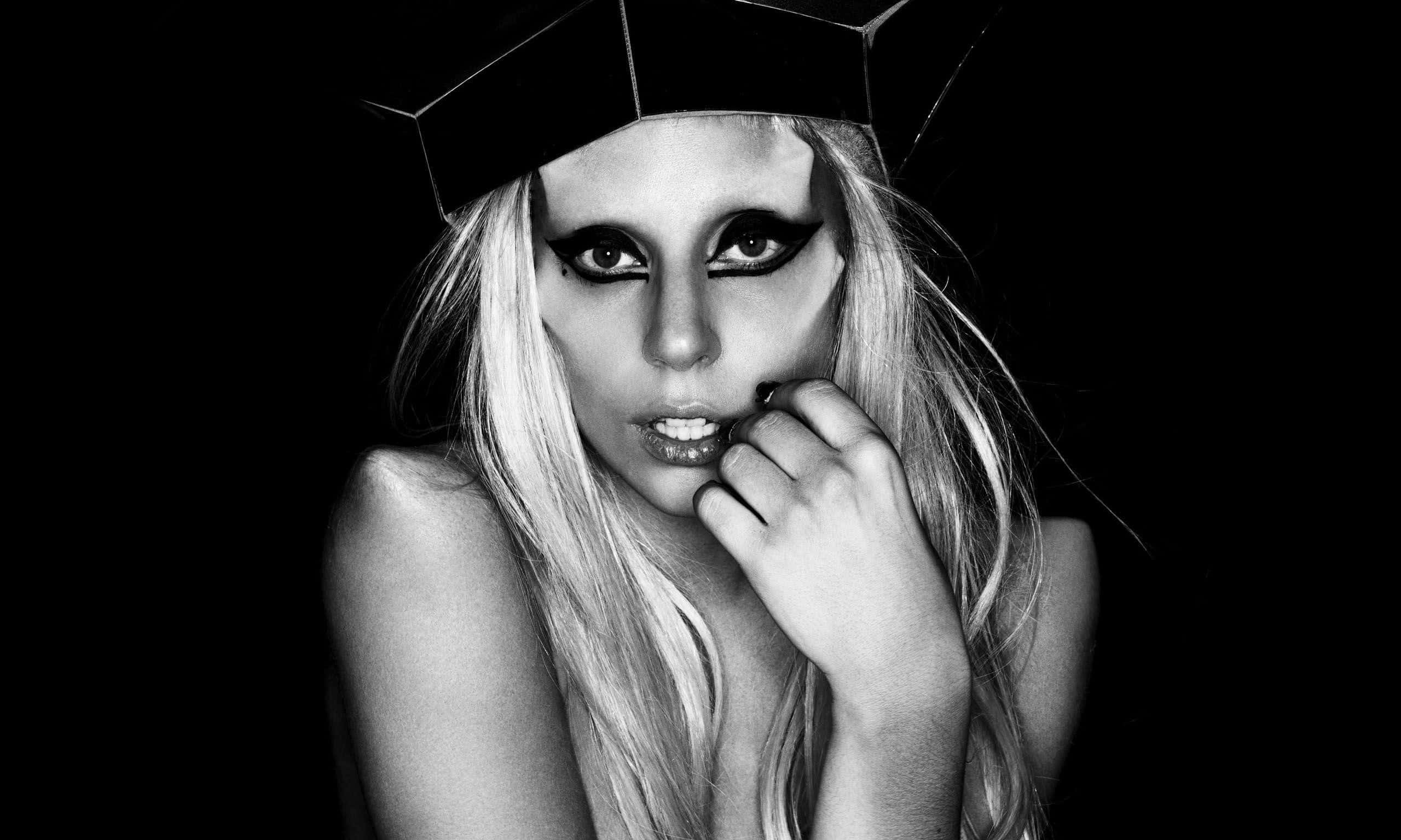 Lady Gaga 桌布 壁紙 — 一個引人注目的黑白肖像，一位女性在深色背景下，擁有鮮明的妝容和幾何頭飾。