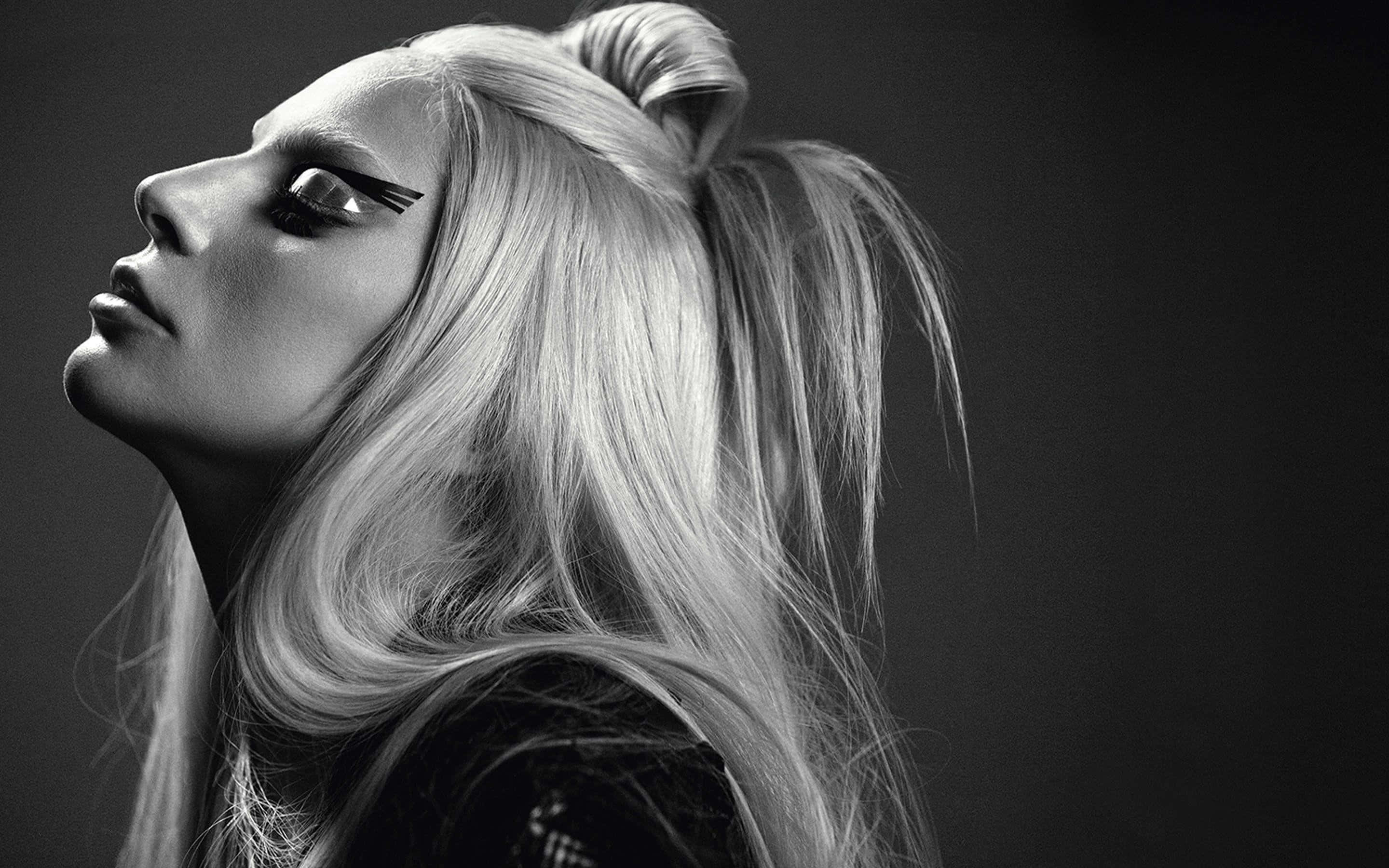 Lady Gaga 桌布 壁紙 — 一個引人注目的黑白肖像，一位金髮高馬尾的女性，用戲劇性的眼線筆向上凝視。