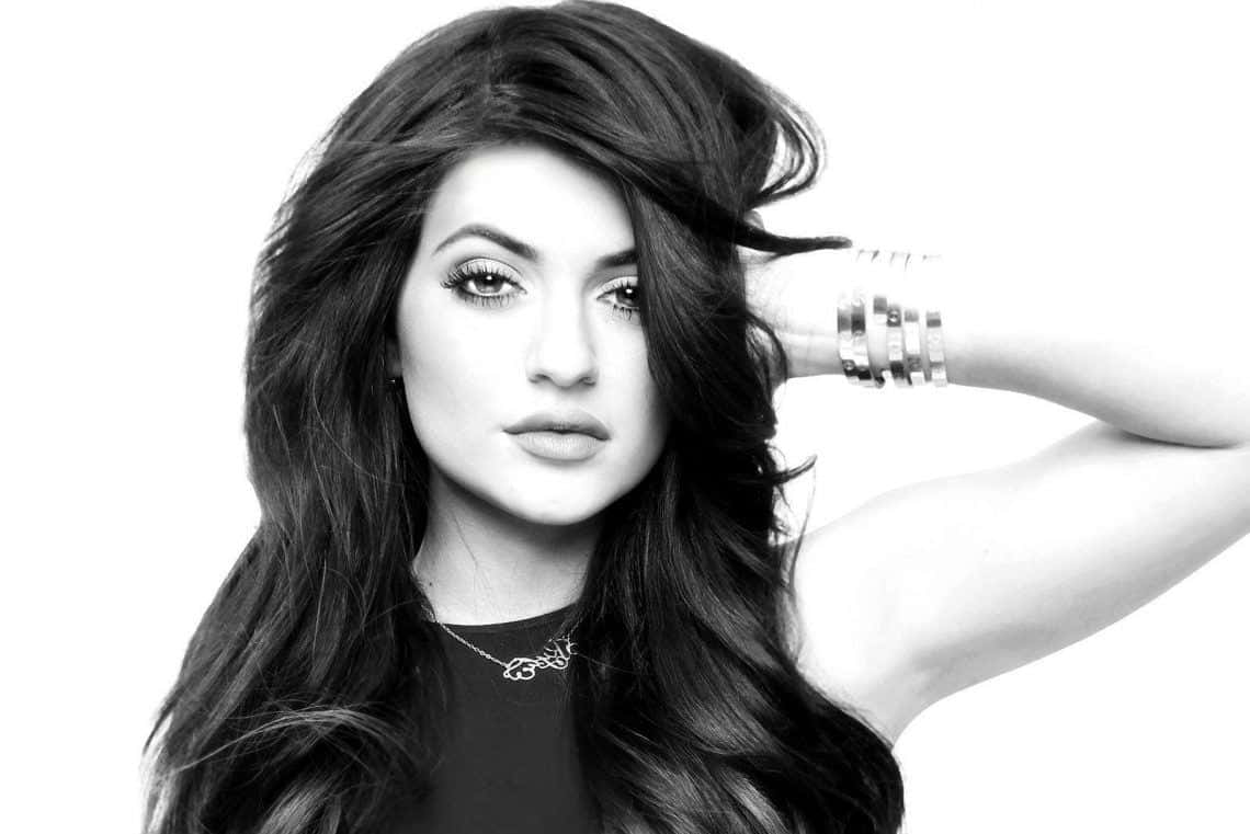 Kylie Jenner 桌布 壁紙 — 一個引人注目的黑白肖像，一位長著長波浪髮的女性在純白背景前擺姿勢。