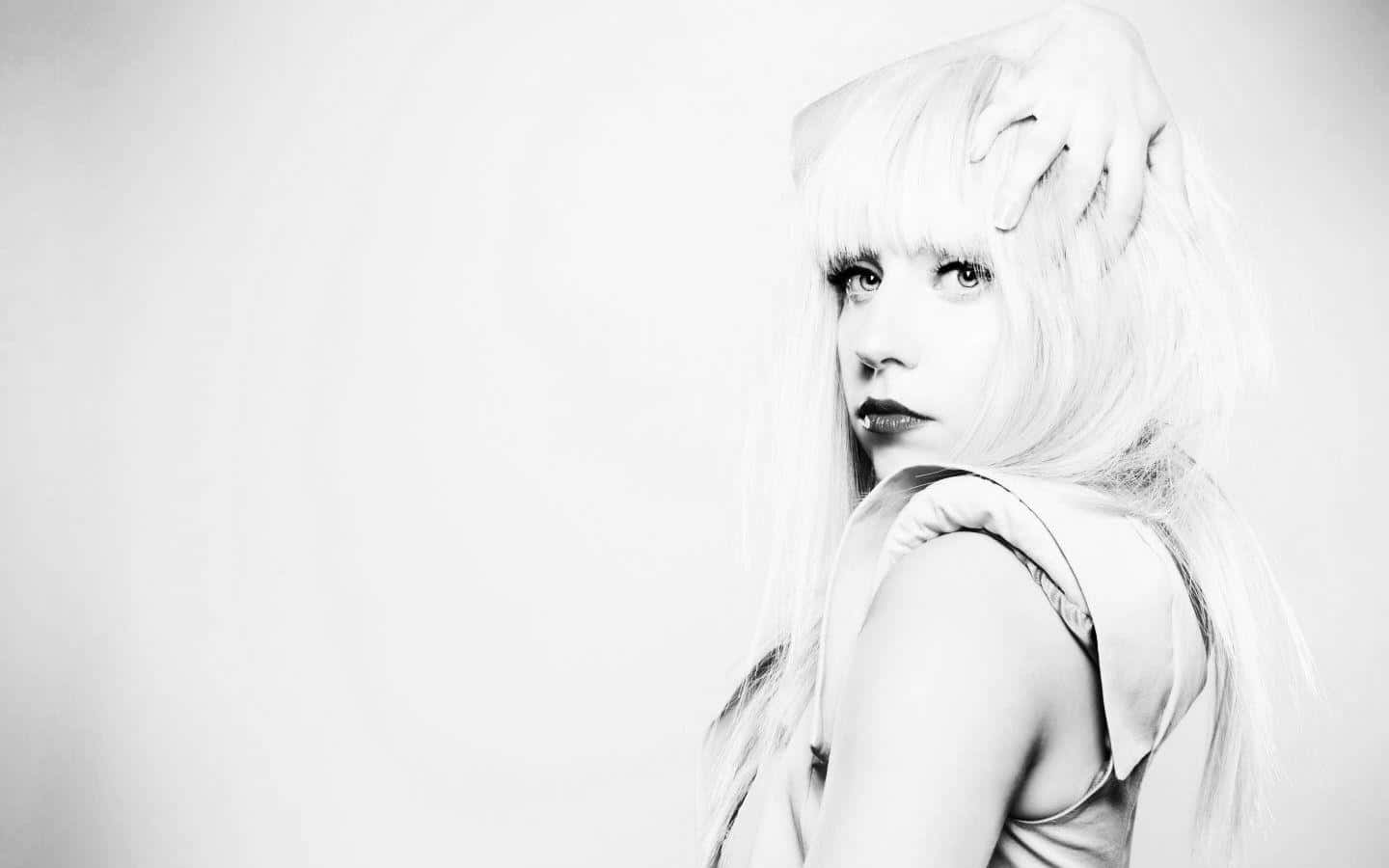 Lady Gaga 桌布 壁紙 — 一個引人注目的黑白肖像，一位長長金髮的女性將手放在頭上，回頭望向肩膀。
