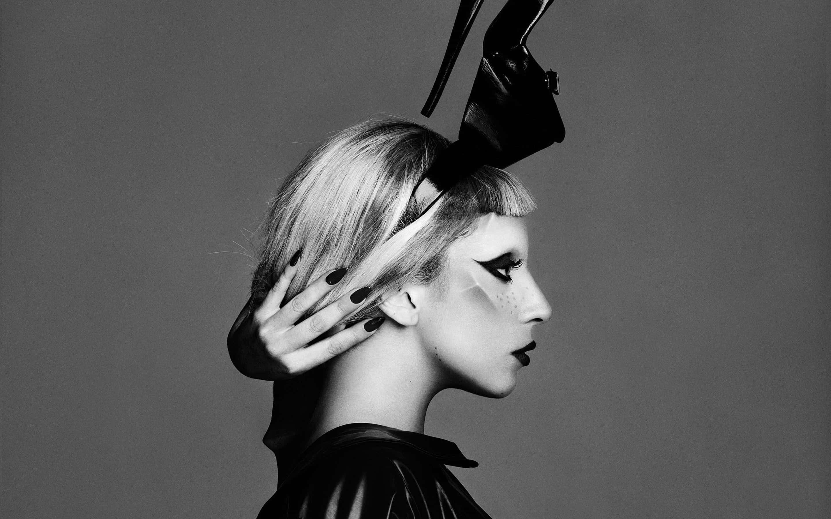 Lady Gaga 桌布 壁紙 — 一個引人注目的黑白肖像，側面輪廓的女性，帶有戲劇性的化妝，頭上放著一雙高跟鞋。