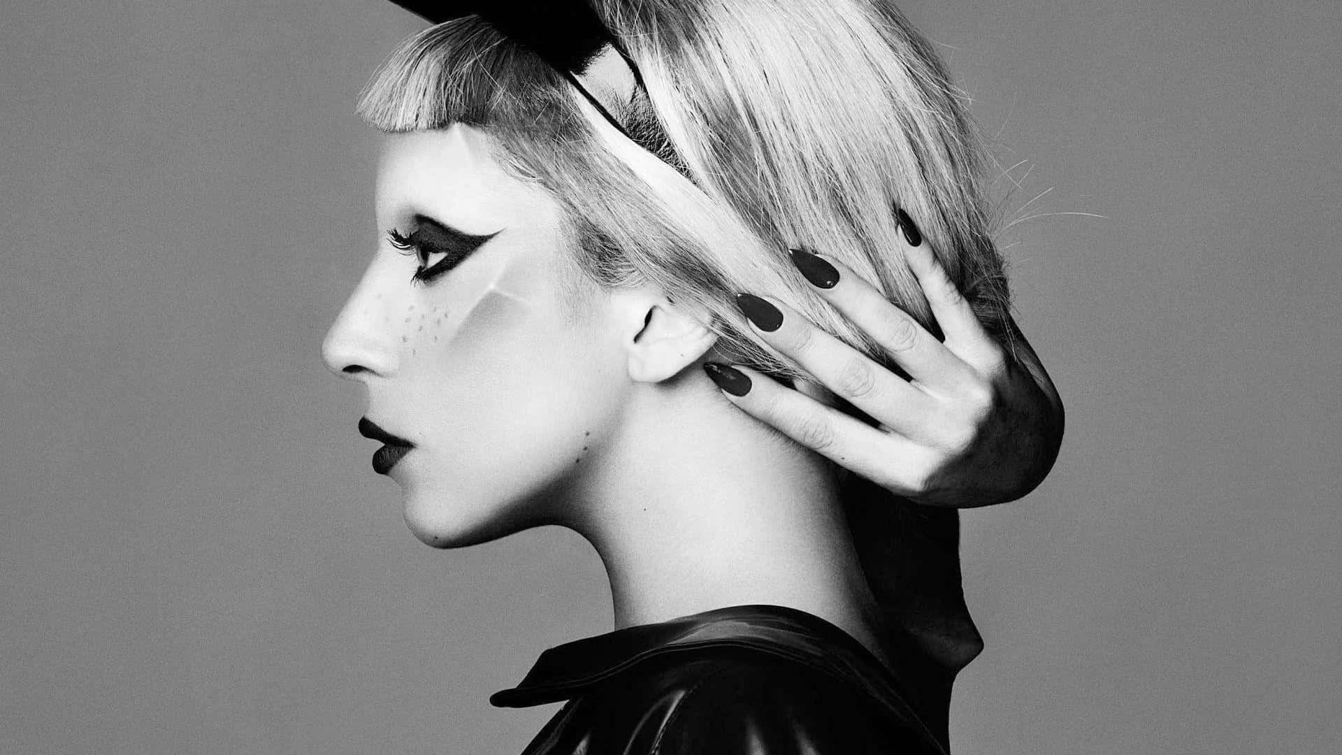 Lady Gaga 桌布 壁紙 — 一個引人注目的黑白肖像，側面輪廓的女性，化著大膽的妝容，手放在頭上，背景是純灰色。