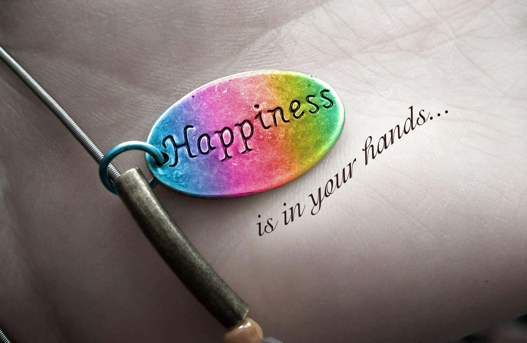 happiness 桌布 壁紙 — 一個彩虹色的橢圓形飾物上刻有「Happiness」，放在一隻手上，旁邊寫著「is in your hands...」。