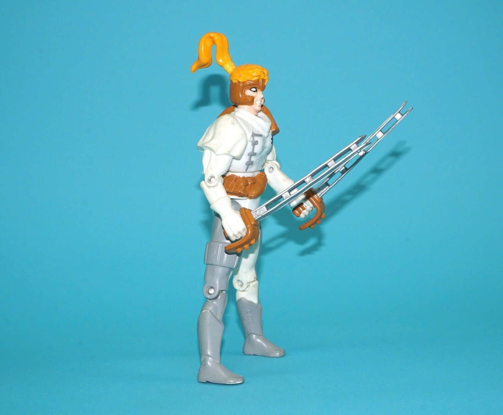 Shatterstar 桌布 壁紙 — 一個復古動作人偶，橙色馬尾辮和銀色武器，在純藍色背景前擺出姿勢。