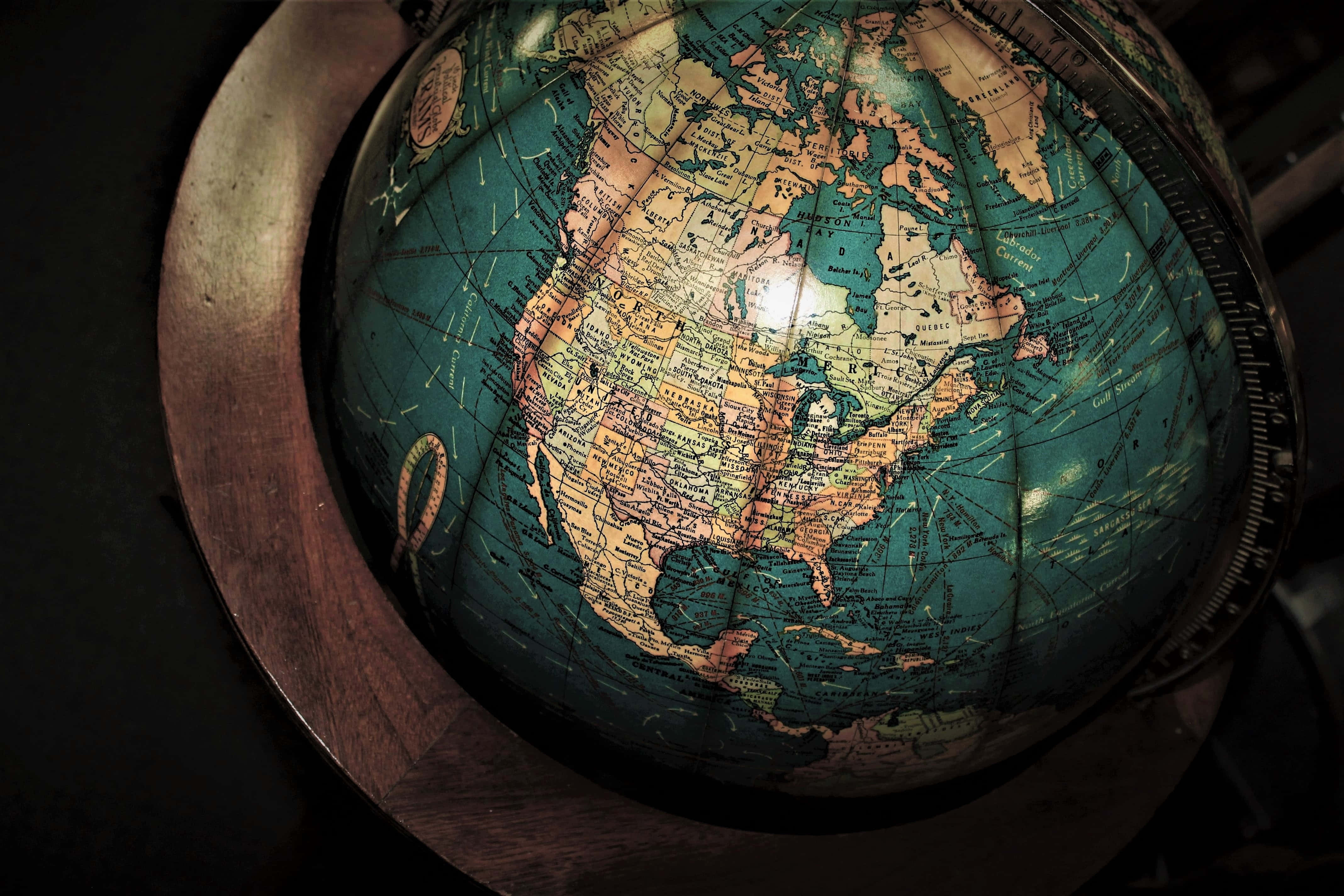 World 桌布 壁紙 — 一個復古地球儀，細節豐富的大陸和藍綠色海洋，在黑暗背景下被聚光燈照亮。