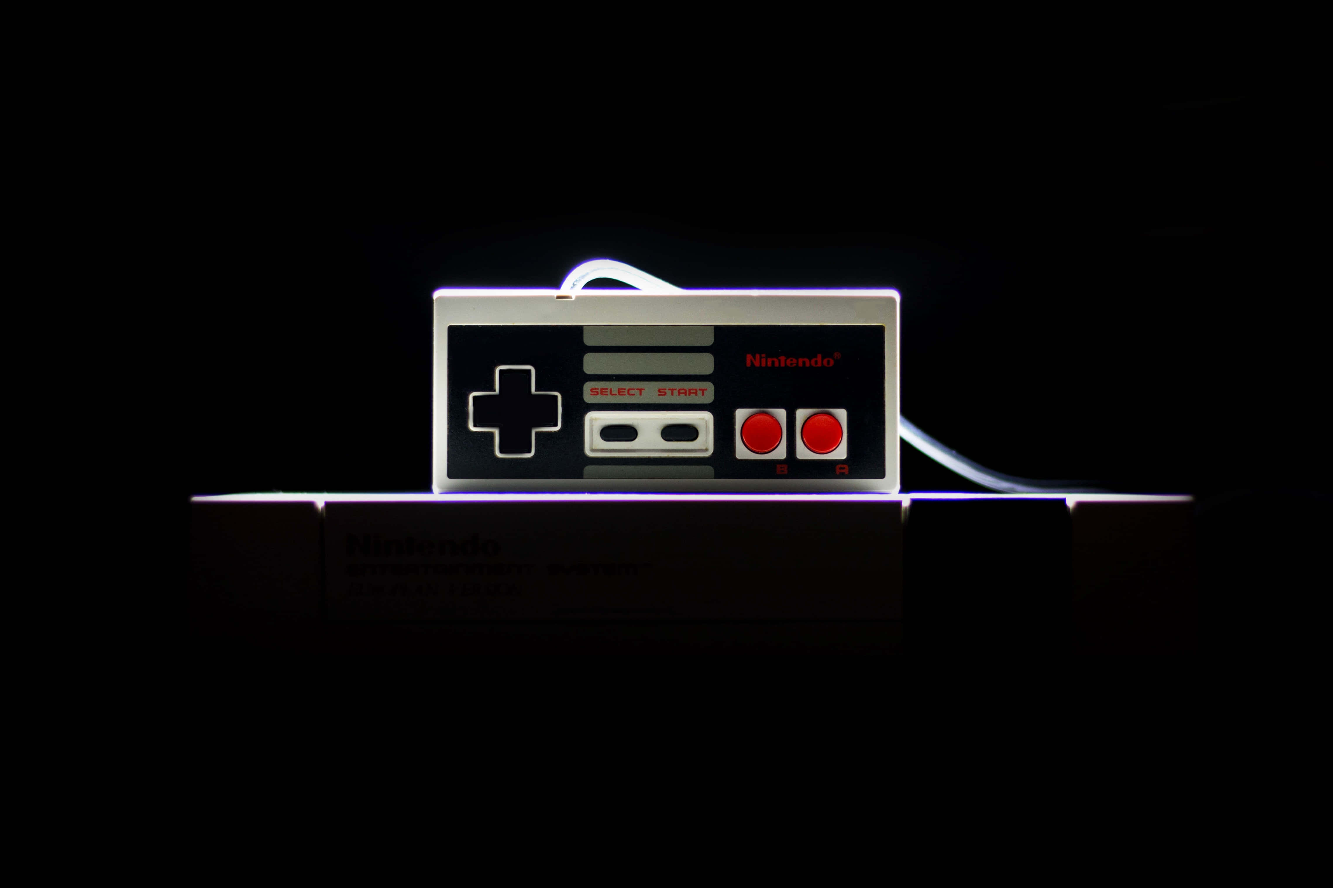 Dark Gaming 桌布 壁紙 — 一個復古的Nintendo Entertainment System控制器在漆黑背景上發出霓虹光芒。