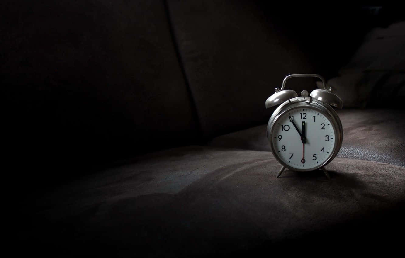 Time 桌布 壁紙 — 一個復古銀色鬧鐘放在深色紋理表面上，在昏暗房間的戲劇性聚光燈下。