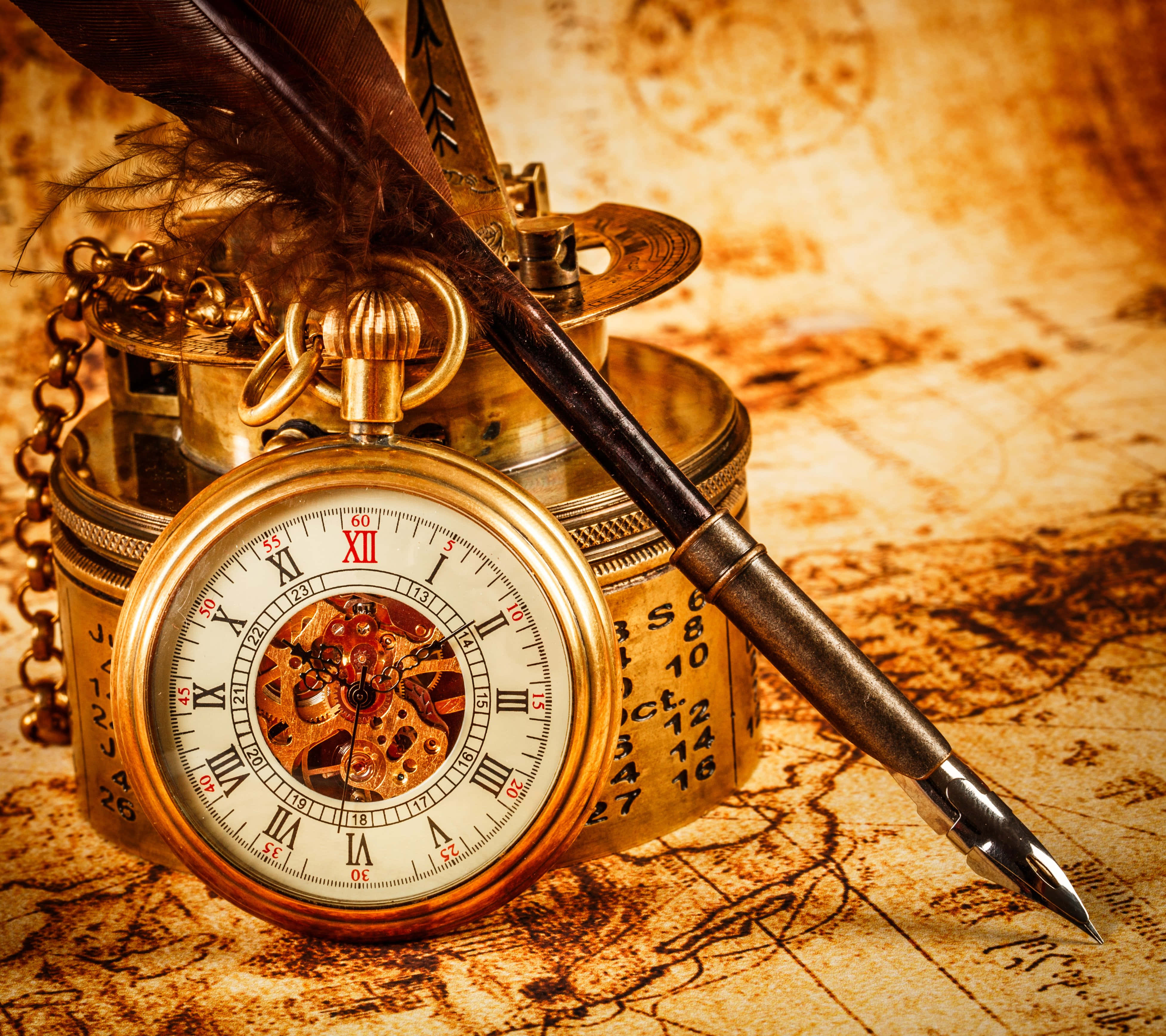 Time 桌布 壁紙 — 一個復古黃銅懷錶，露出齒輪，擱在一張陳舊羊皮紙地圖上，旁邊有一支羽毛筆。