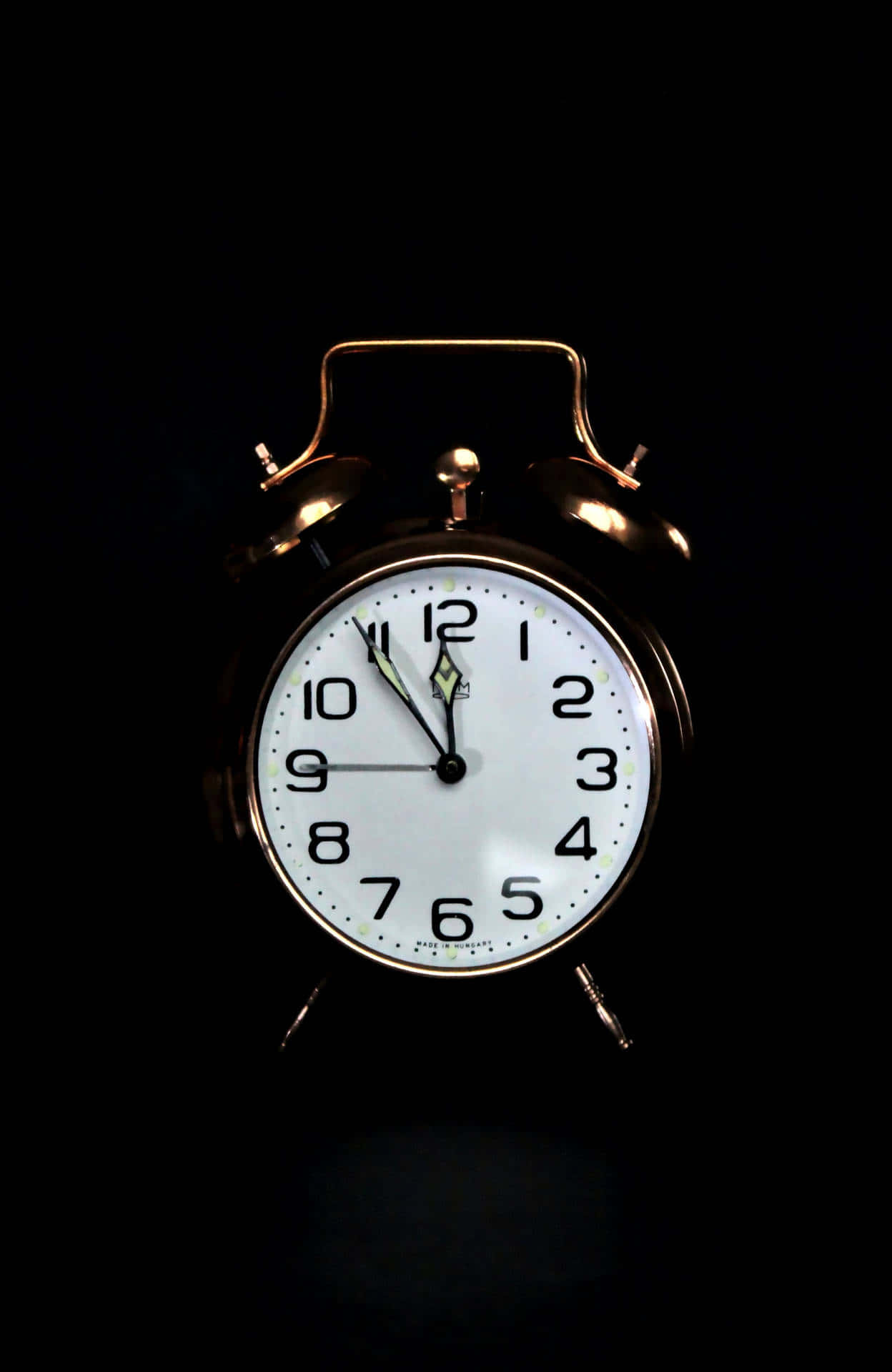 Clocks 桌布 壁紙 — 一個復古黃銅鬧鐘，白色錶盤配黑色數字，在漆黑背景中發光。