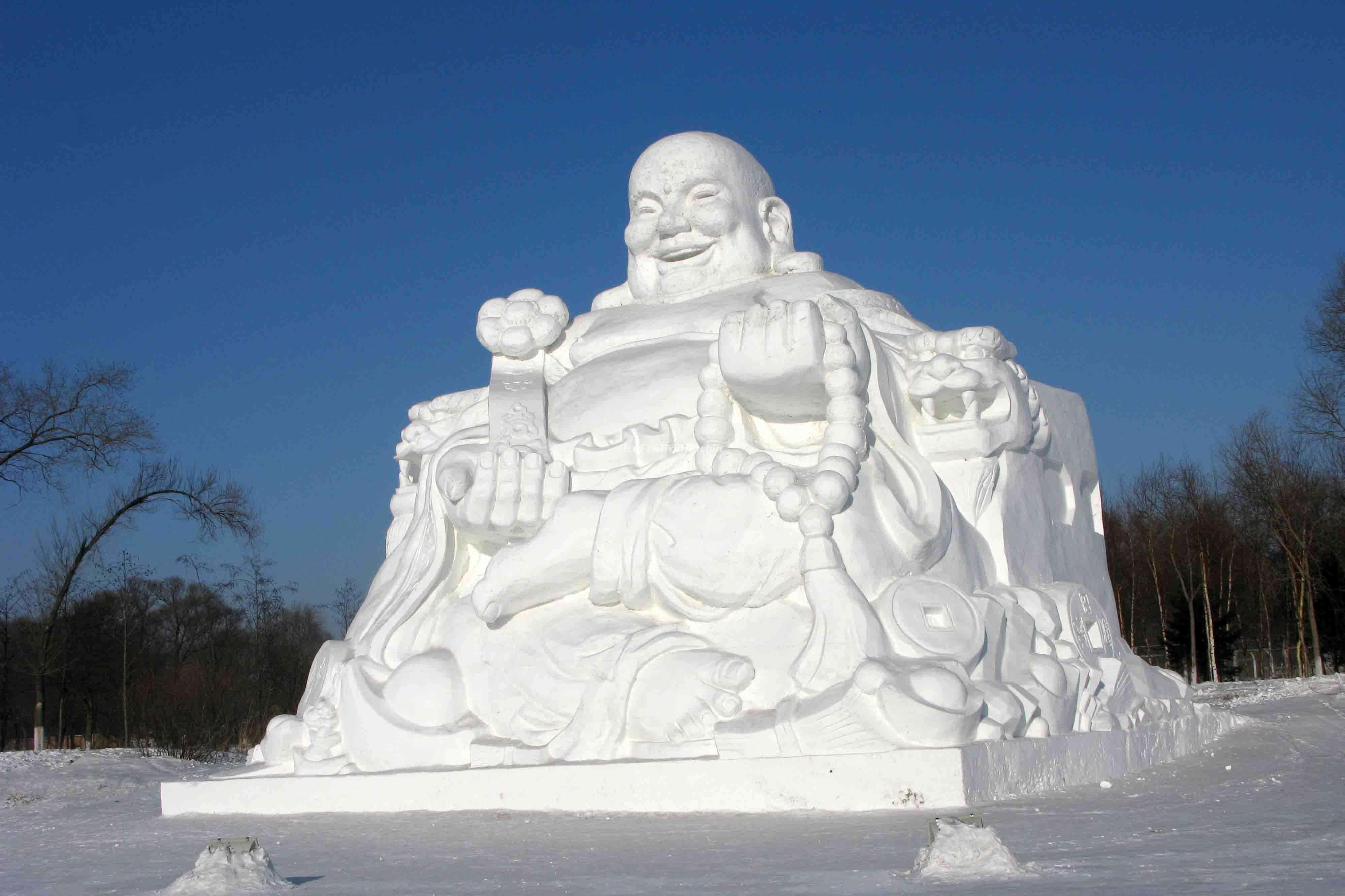 Ice Sculpture 桌布 壁紙 — 一個微笑佛陀的巨大雪雕，在晴朗的藍天下，靜靜地坐在冬季公園中。