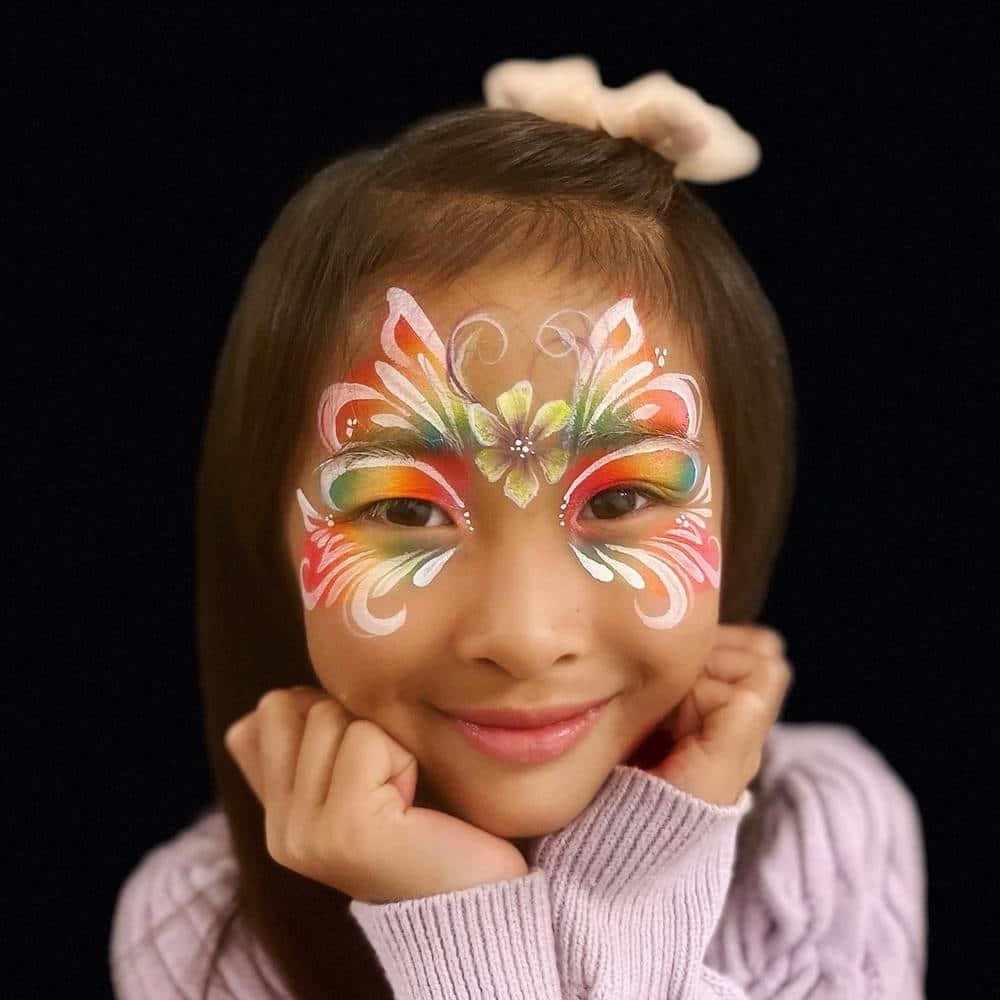 臉上畫著彩色蝴蝶圖案的孩子，雙手托腮微笑。 — 唯美蝴蝶動圖 壁紙