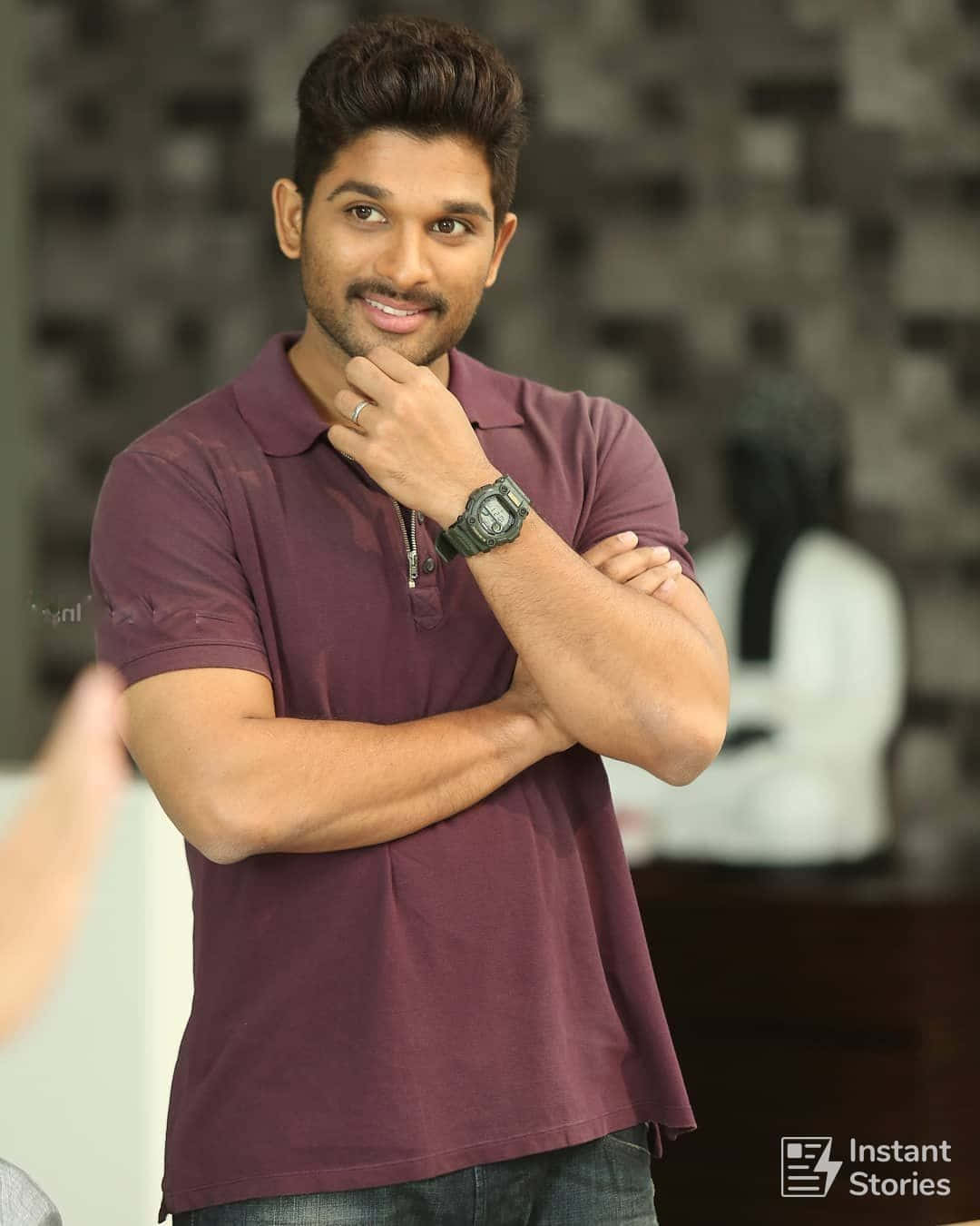 Allu Arjun 桌布 壁紙 — 一個微笑的男人穿著栗色Polo衫，雙臂交叉，手托下巴，靠著模糊的紋理牆壁擺姿勢。