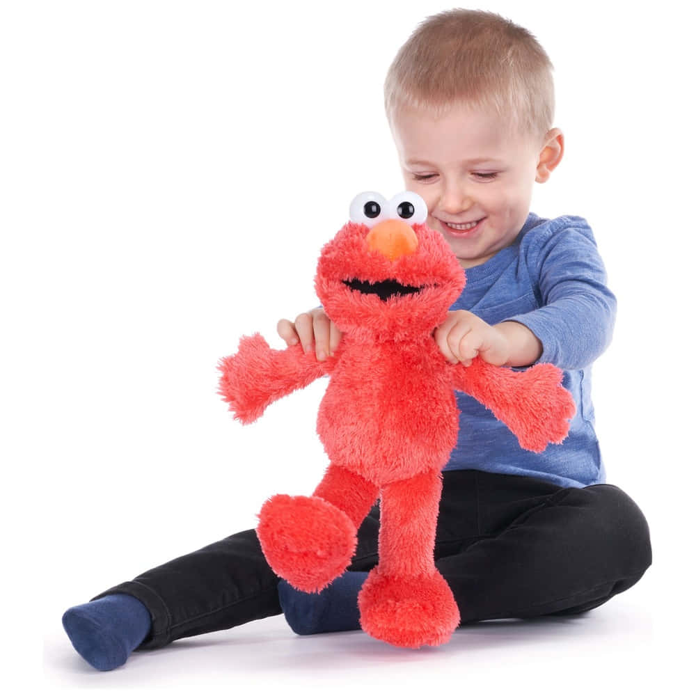 Elmo 桌布 壁紙 — 一個快樂嘅幼兒著住藍色衫，喺純白背景前攬住一個毛茸茸嘅紅色 Elmo 毛公仔。