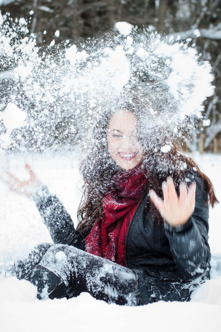 Winter Photography 桌布 壁紙 — 一個快樂的女人坐在雪地森林裡，一邊開心地將雪拋向空中，一邊大笑。