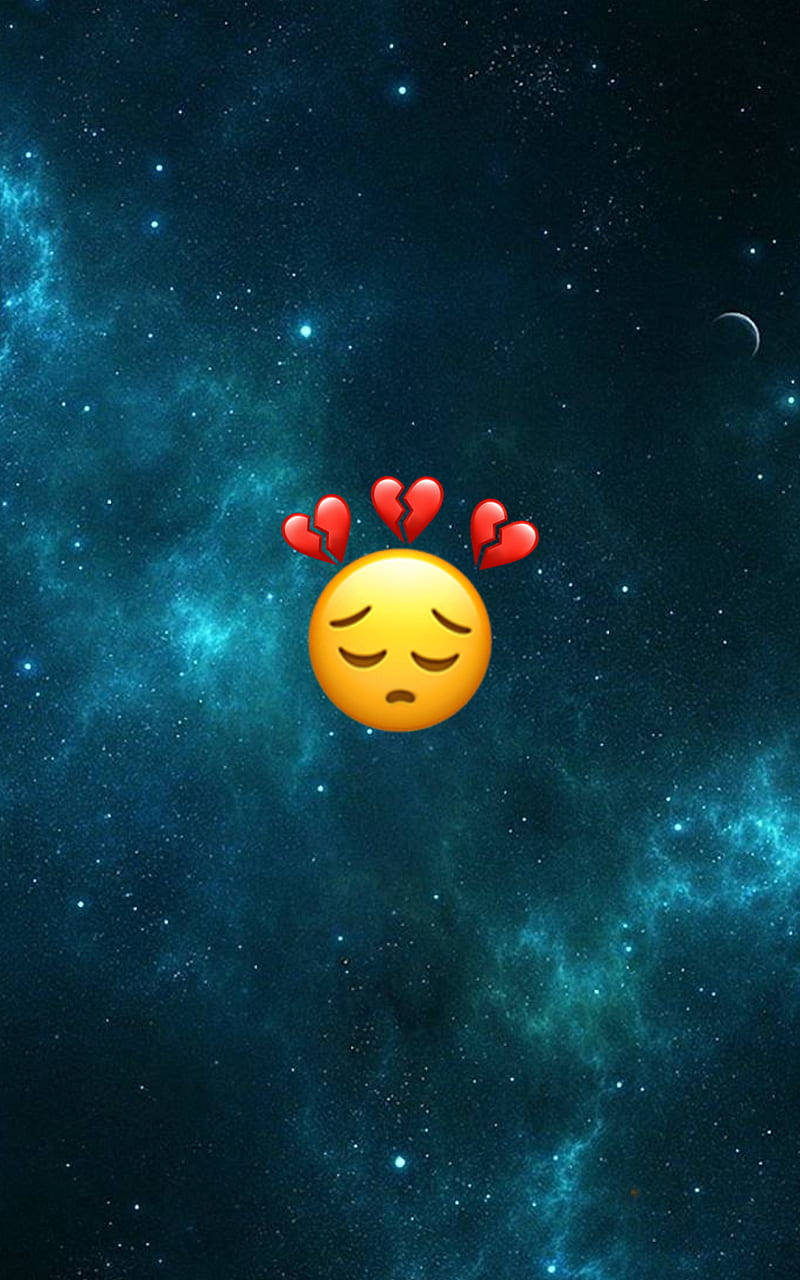 Sad Emoji 桌布 壁紙 — 一個悲傷的黃色表情符號，帶有破碎的心，漂浮在充滿活力的青綠色和深藍色星空星雲中，伴隨著一彎新月。