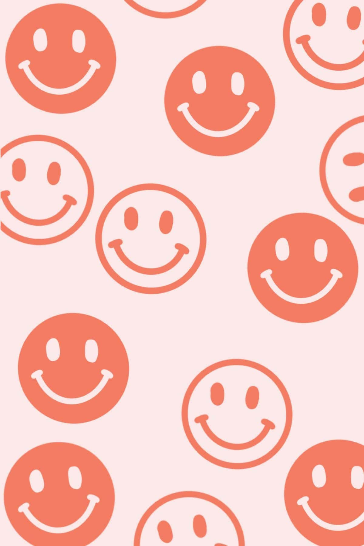 Aesthetic Smiley Face 桌布 壁紙 — 一個愉快的圖案，在柔和的粉紅色背景上，有珊瑚橙色的笑臉。