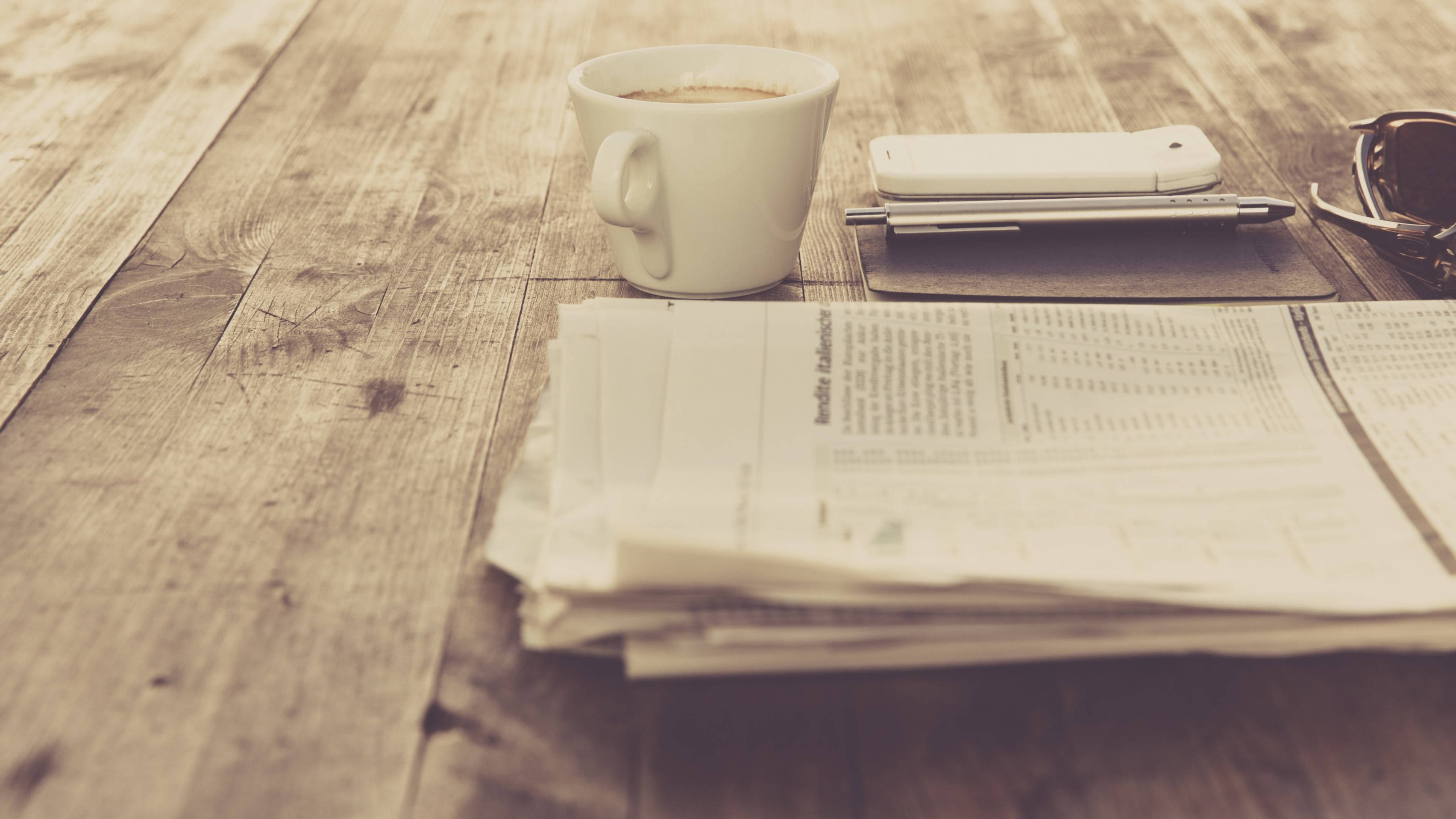 Newspaper 桌布 壁紙 — 一個懷舊咖啡杯、報紙、電話和太陽眼鏡擺放在質樸木桌上的棕褐色調靜物。