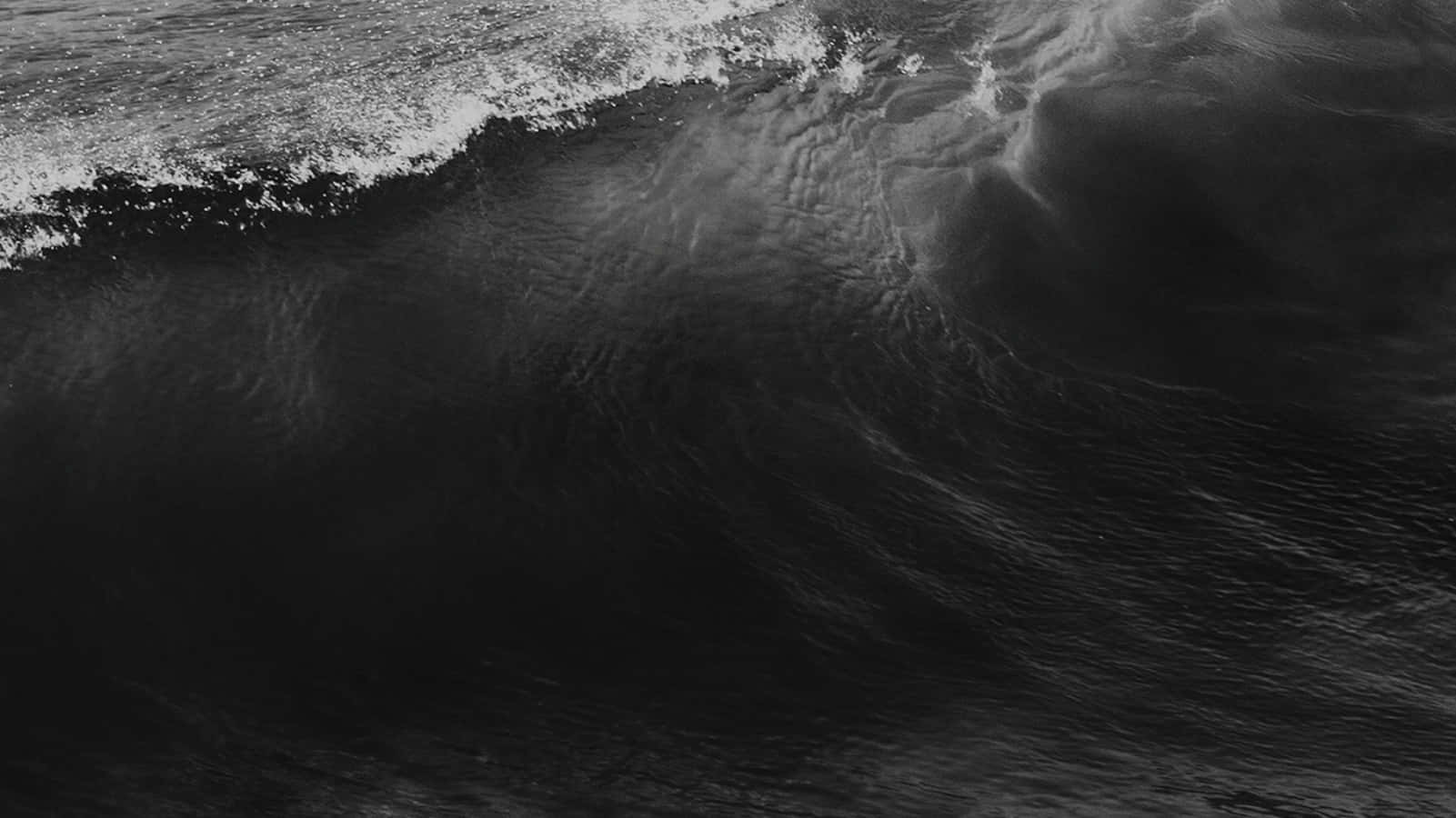 Black Sea 桌布 壁紙 — 一個戲劇性的單色波浪強力捲曲，帶有泡沫般的白色浪花，映襯著深邃陰暗的水面。