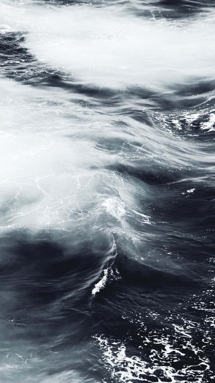 Black And White Ocean 桌布 壁紙 — 一個戲劇性的特寫，呈現深藍色海水中翻騰的海浪與白色泡沫。