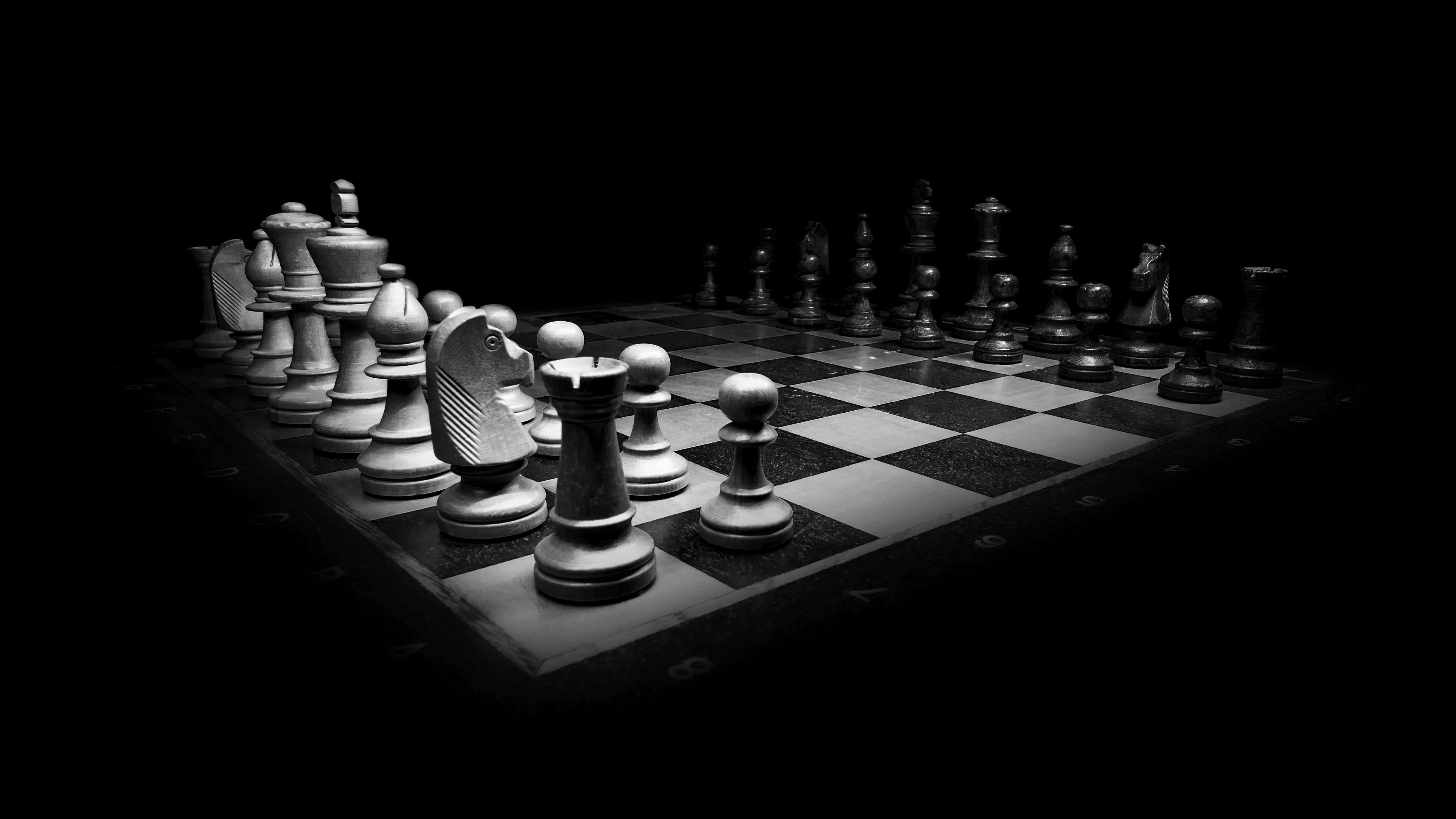 Educational Games 桌布 壁紙 — 一個戲劇性的黑白棋盤，棋子聚焦燈光下，在黑暗虛空中準備戰鬥。